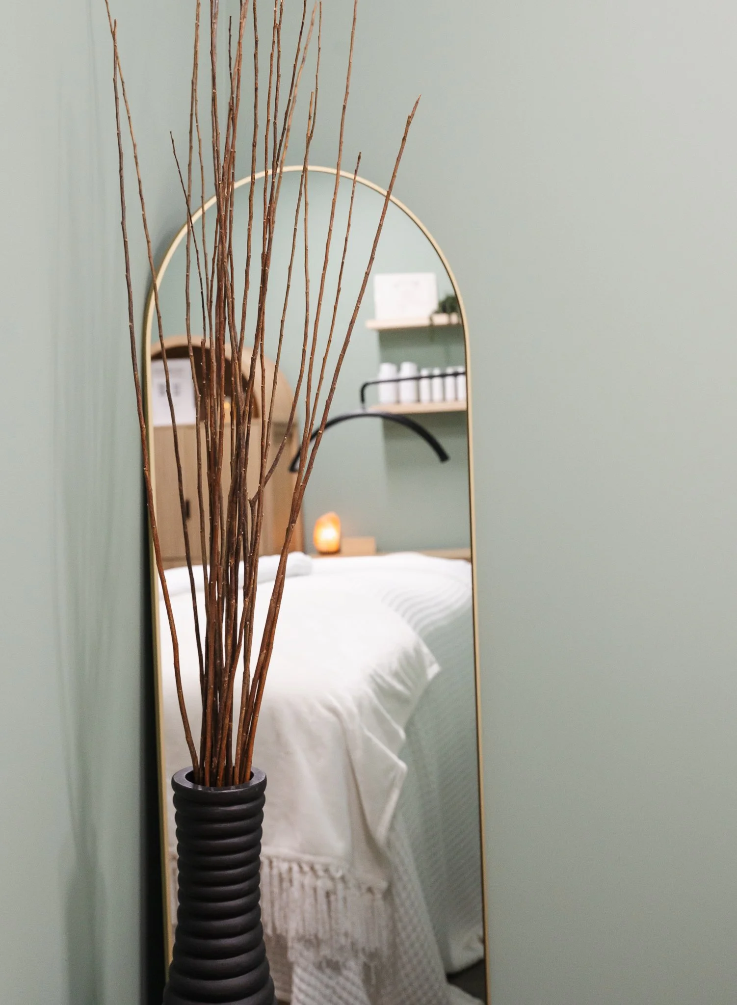 tall mirror reflecting facial treatment bed in esthetician room