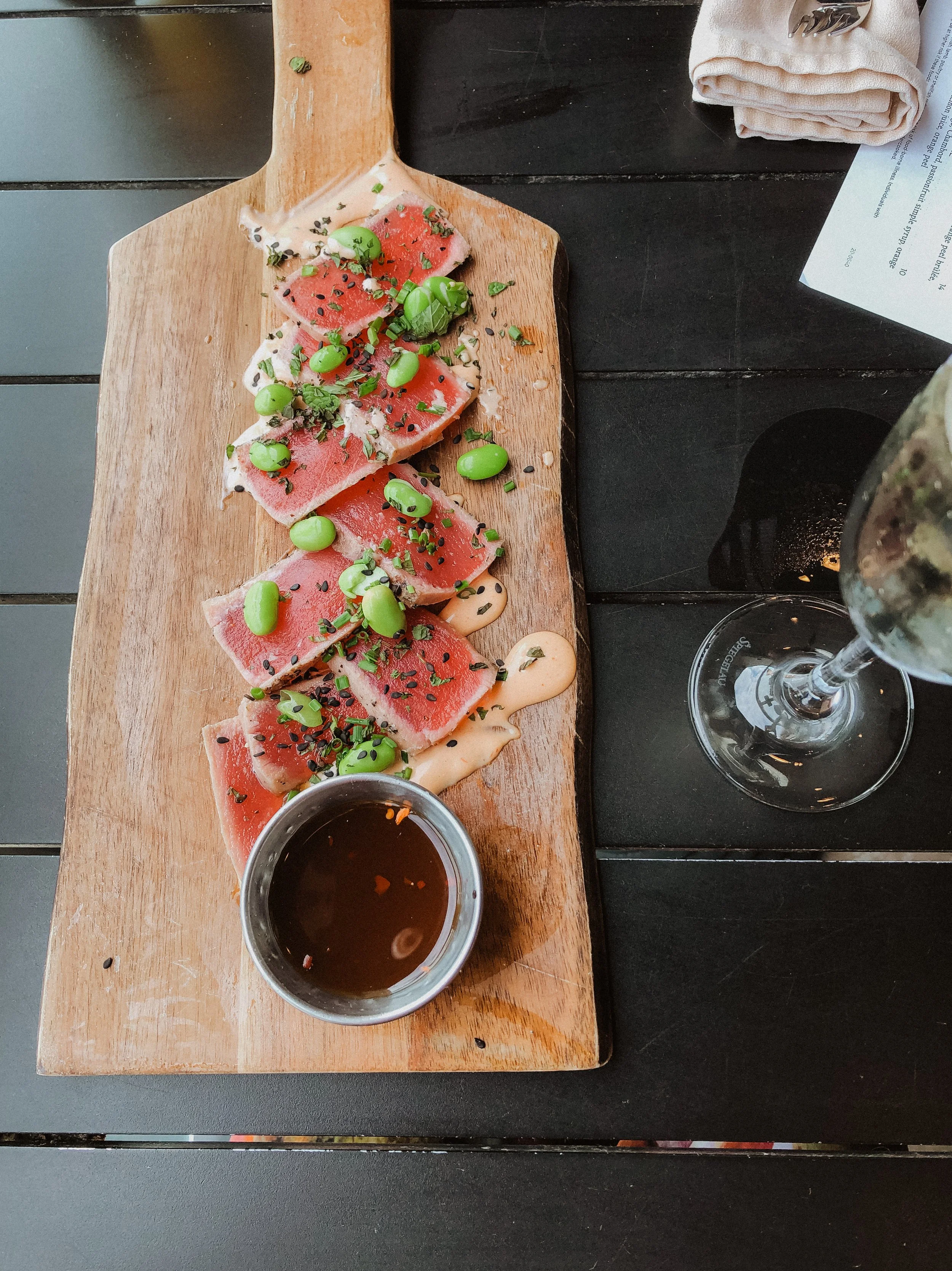  board of seared ahi sitting on table with wine 