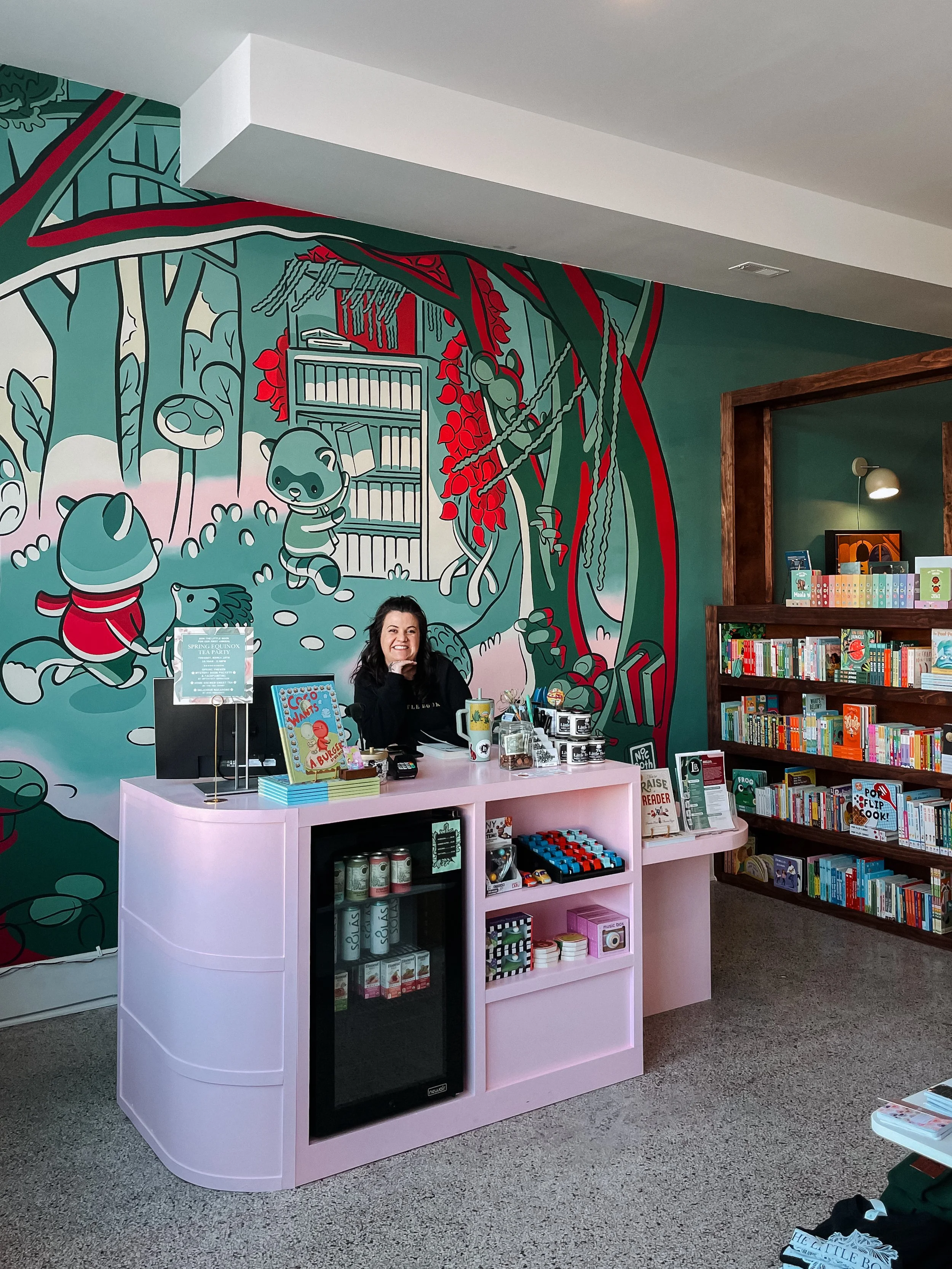 Shop owner of The Little Book smiling at the register of her book shop