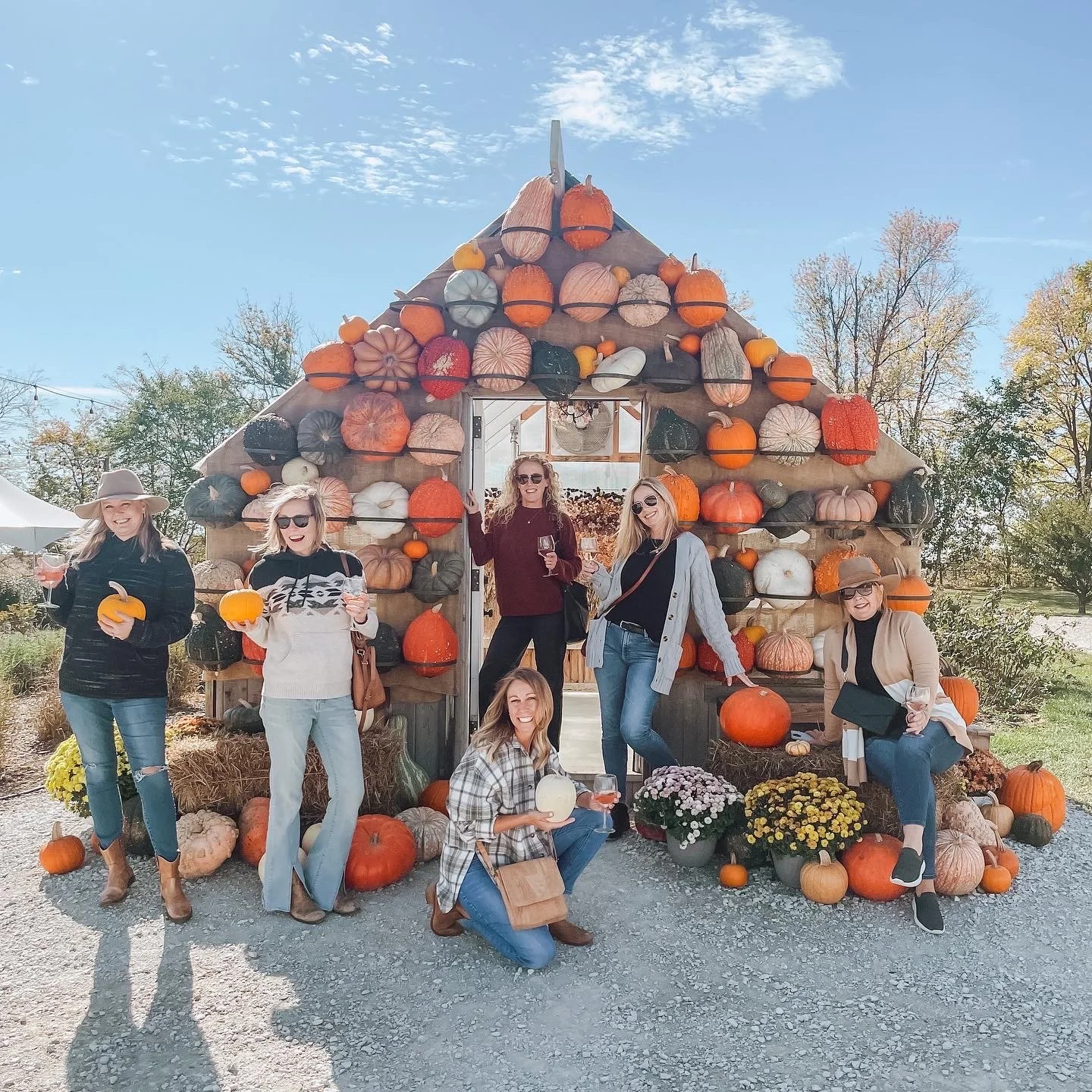group of girlfriends posing in front of Rose Farm greenhouse styled with fall decor