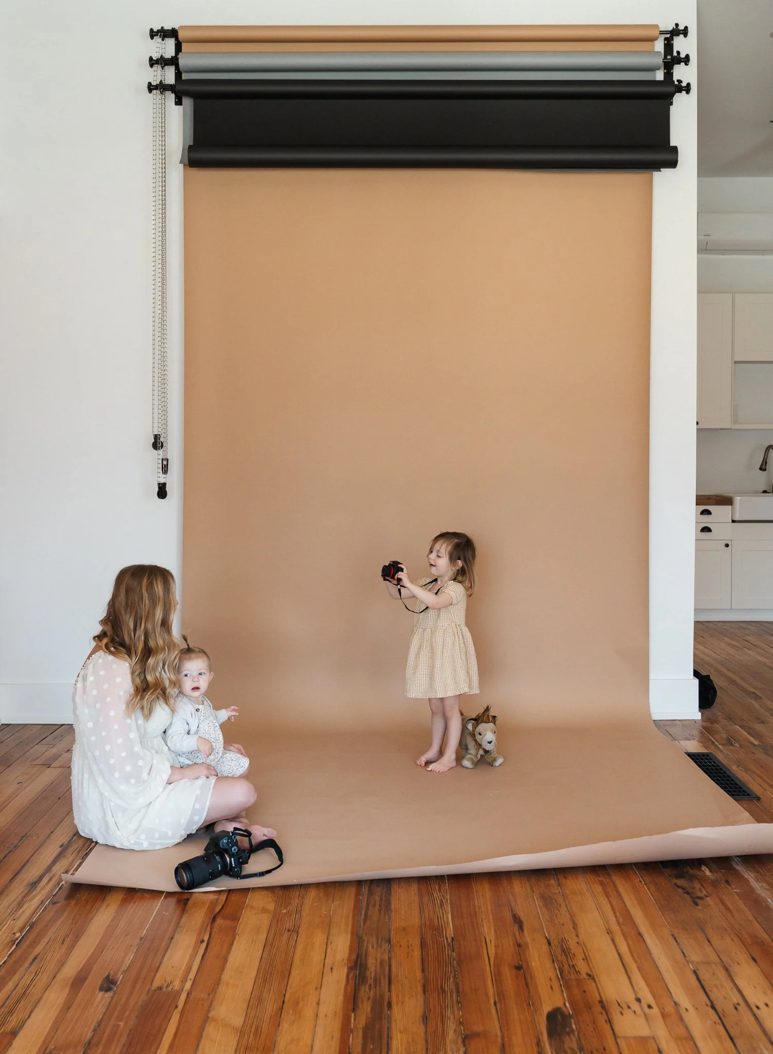 mother sitting on floor of Studio E9 with her two young daughters and her camera