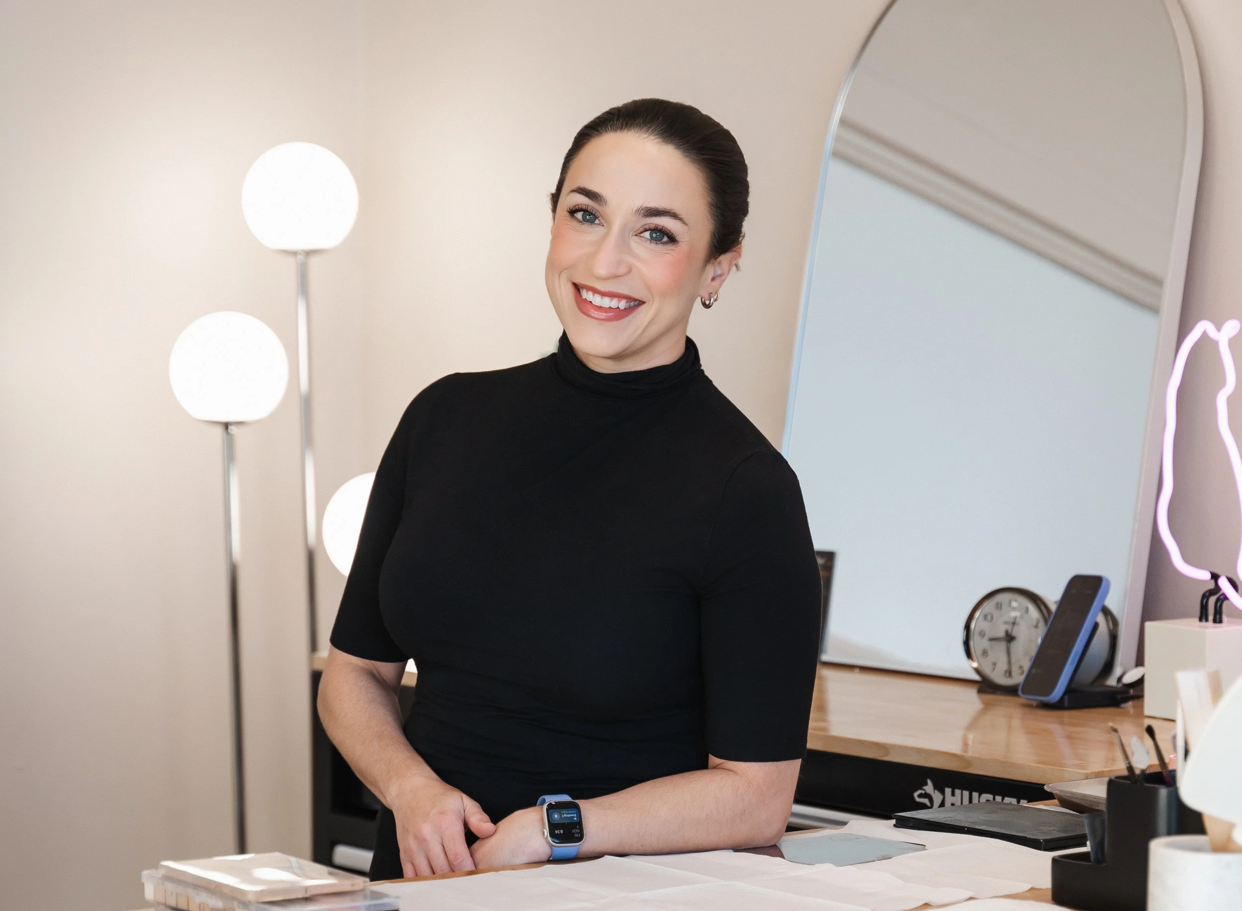 Ivy Boyd leaning on counter and smiling in her makeup studio