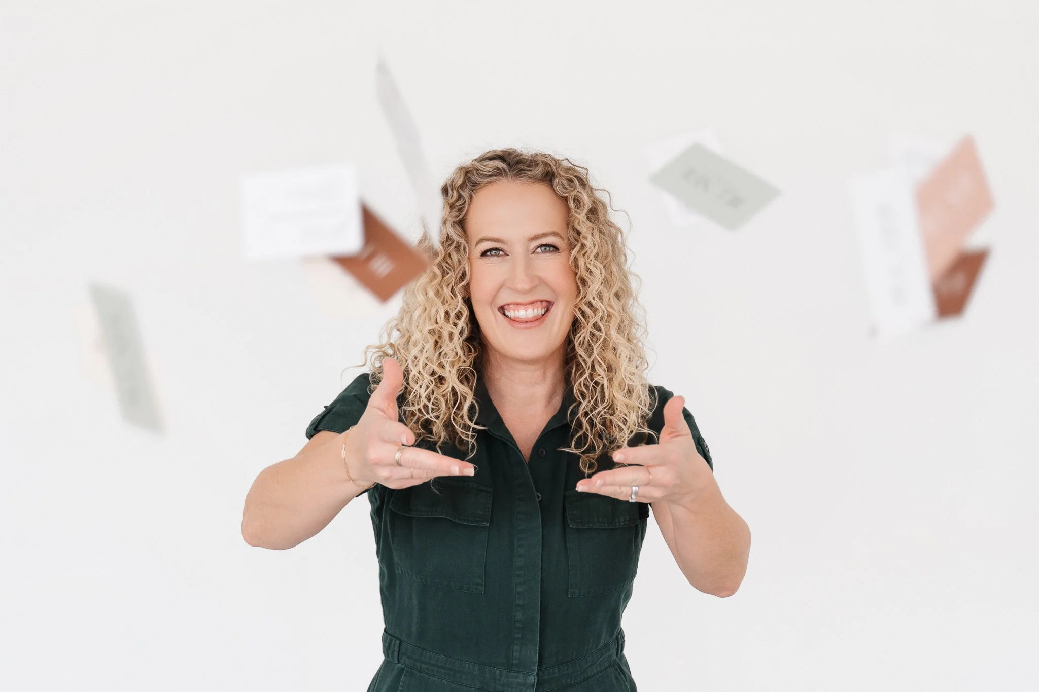 Jill Neil smiling big as she throws her business cards in the air with her logo on them each in a different brand color
