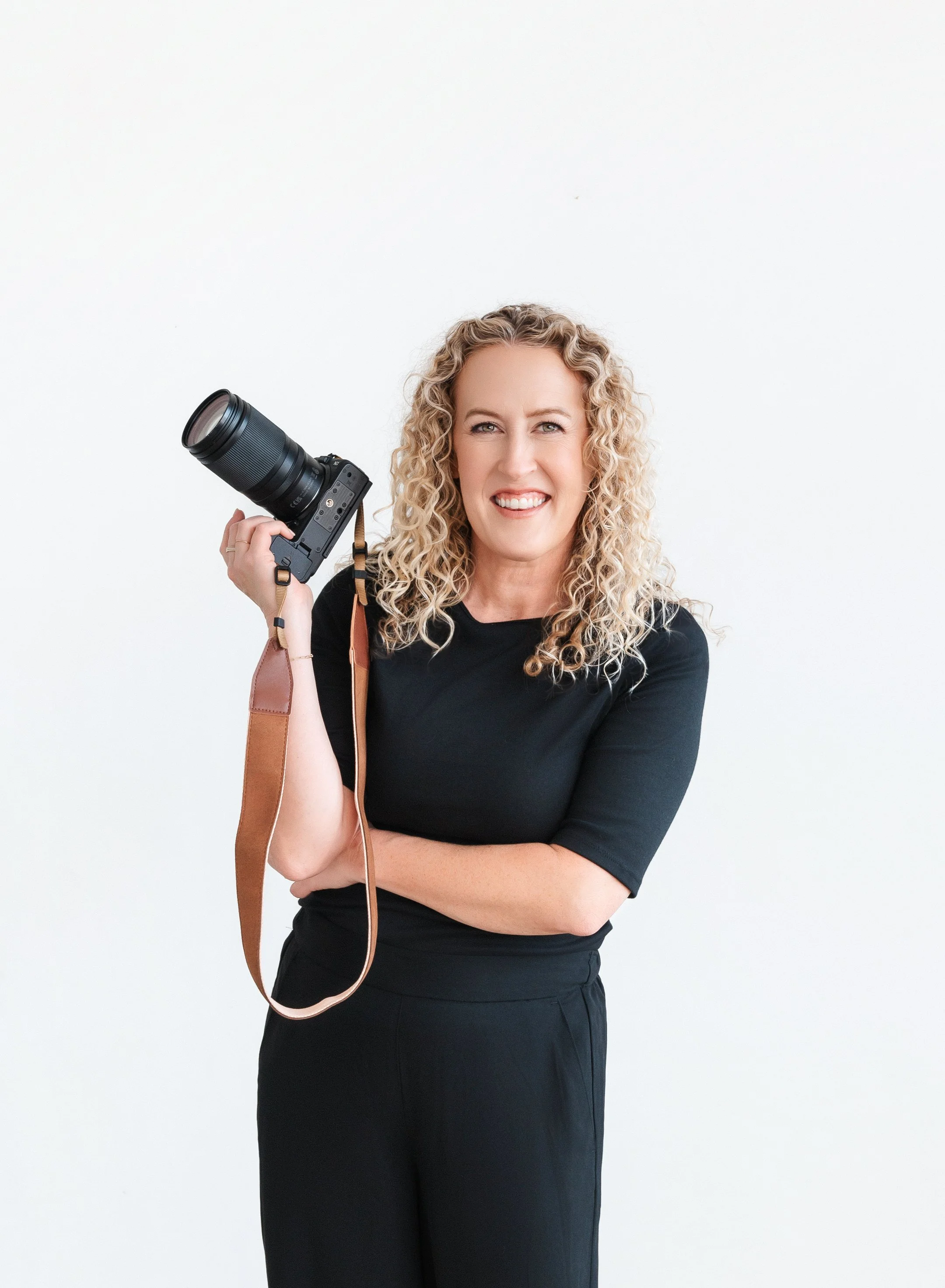 Jill Neil standing with camera in her hand and smiling