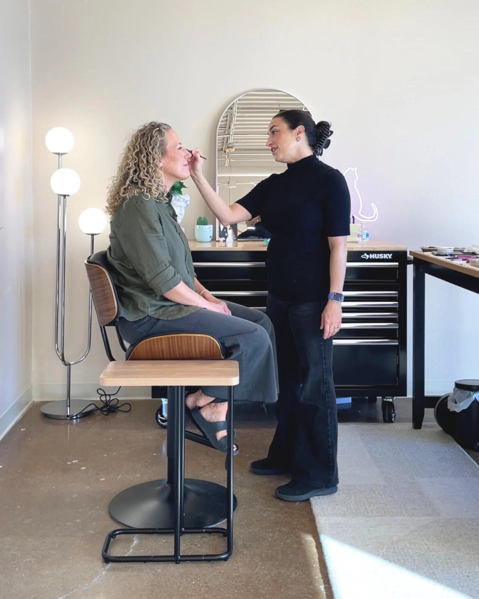 Ivy Boyd applying makeup to Jill Neil in her makeup studio space