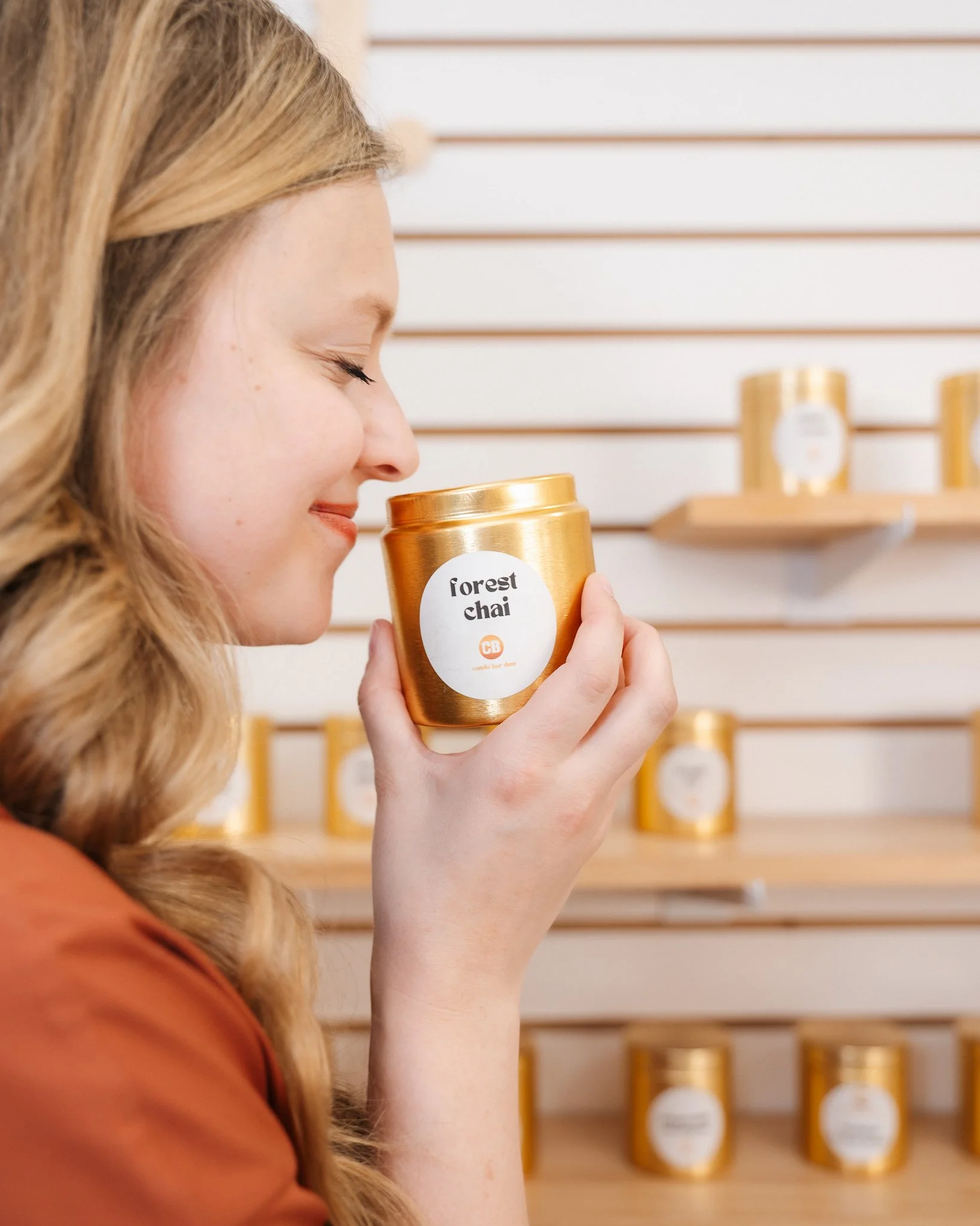 woman smiling with her eyes closed as she smells a forest chai candle scent at Candle Bar DSM