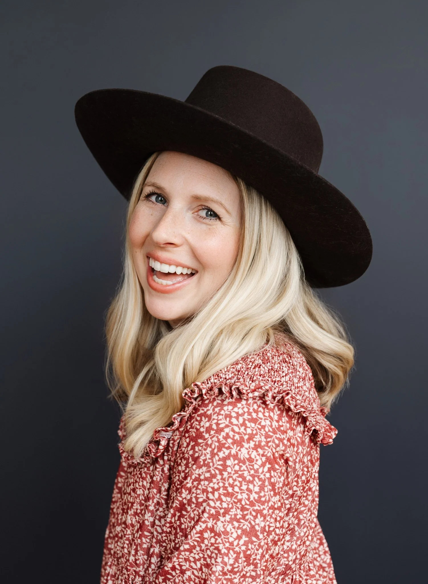 female wearing a large hat and a big open mouth smile