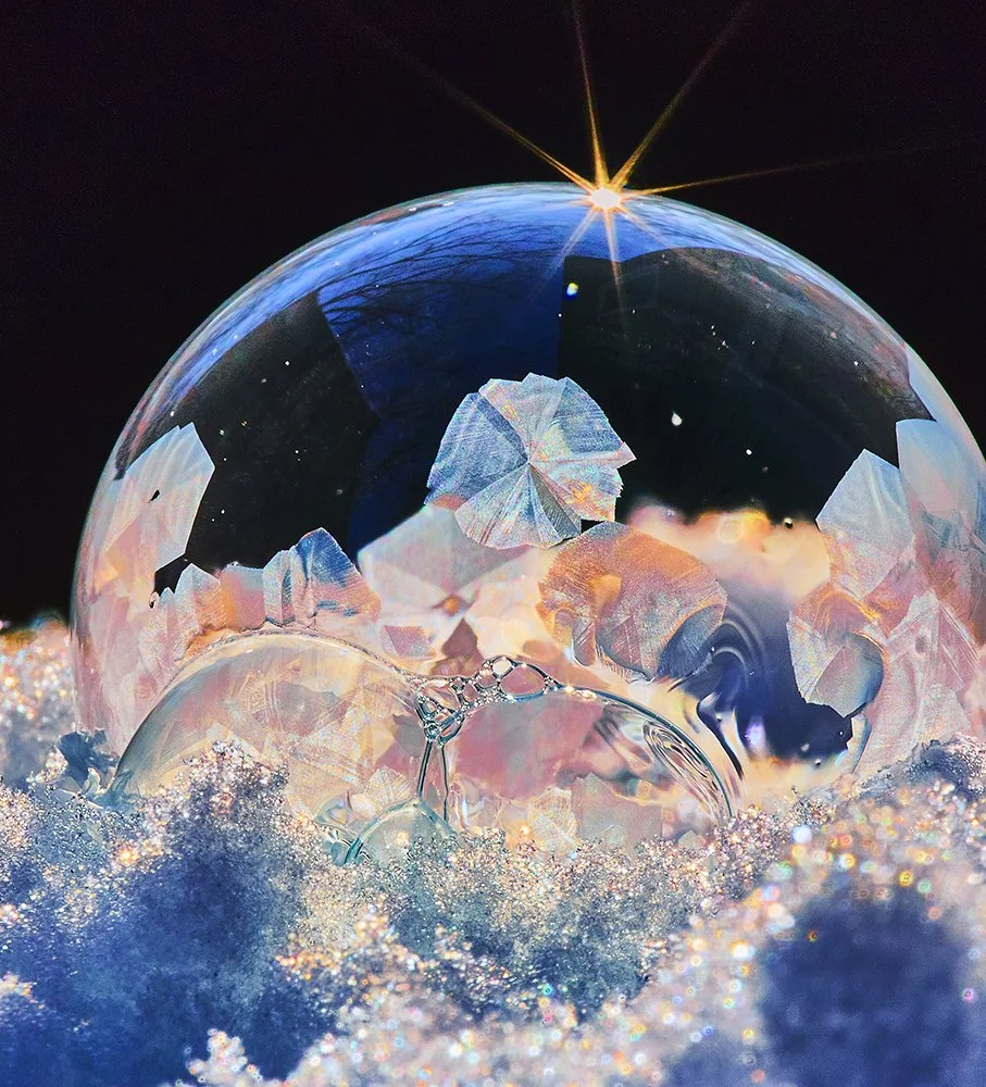 A close-up of a winter soap bubble, with iridescent colors and reflections, backlit by the sun on a freezing cold day in Minnesota.