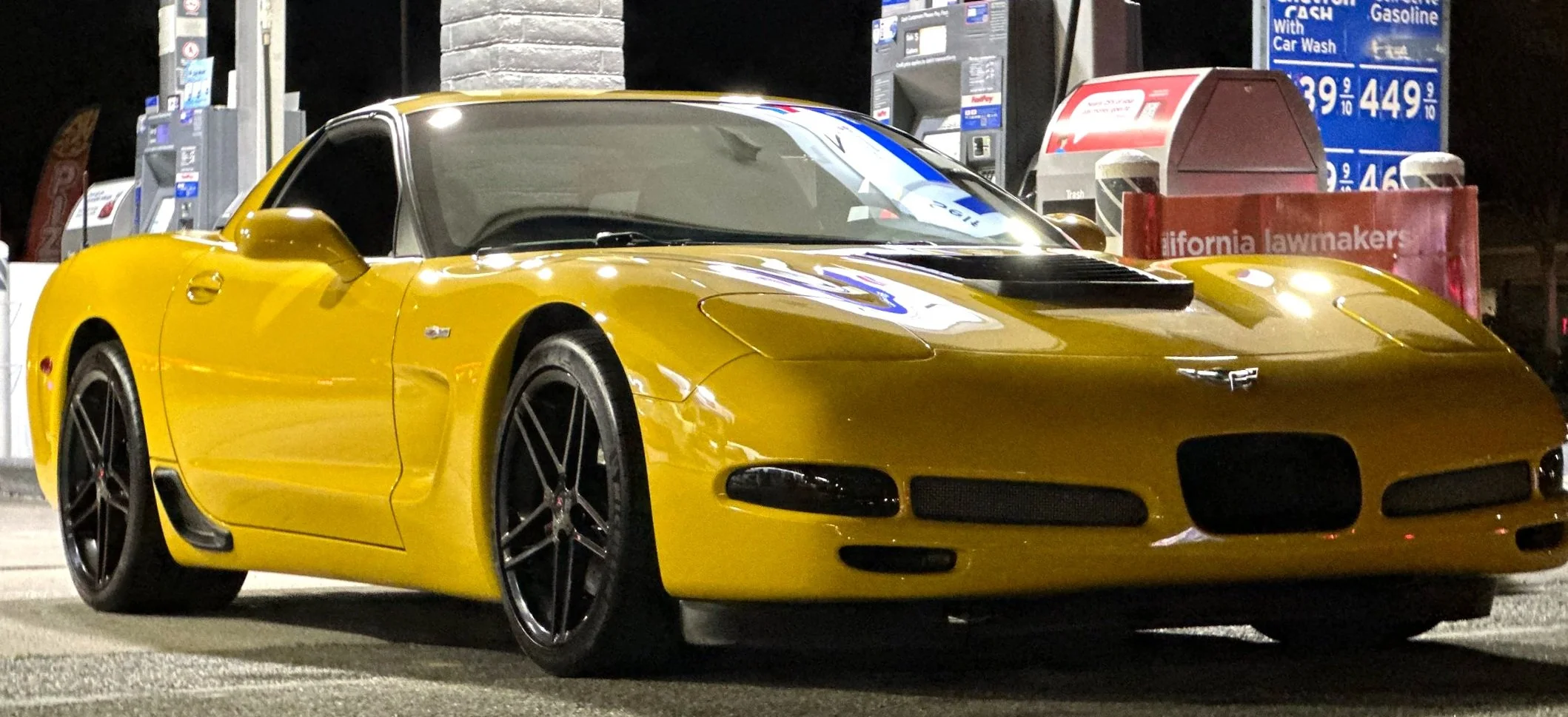 A yellow sports car parked at a gas station at night.