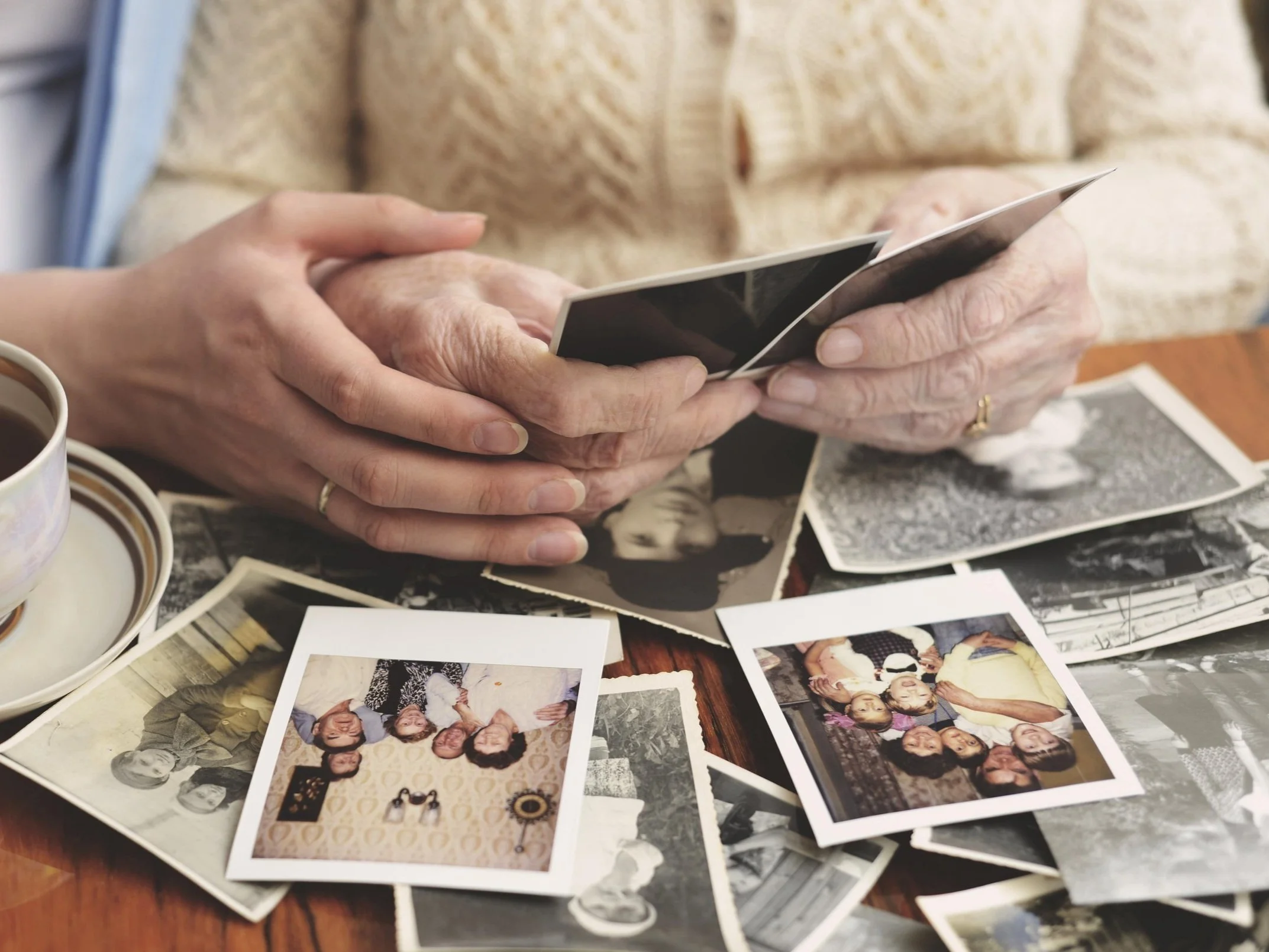 Hands looking at a collection of old photographs, used as a metaphor for reprocessing traumatic memories with EMDR in Tampa and New Port Richey.