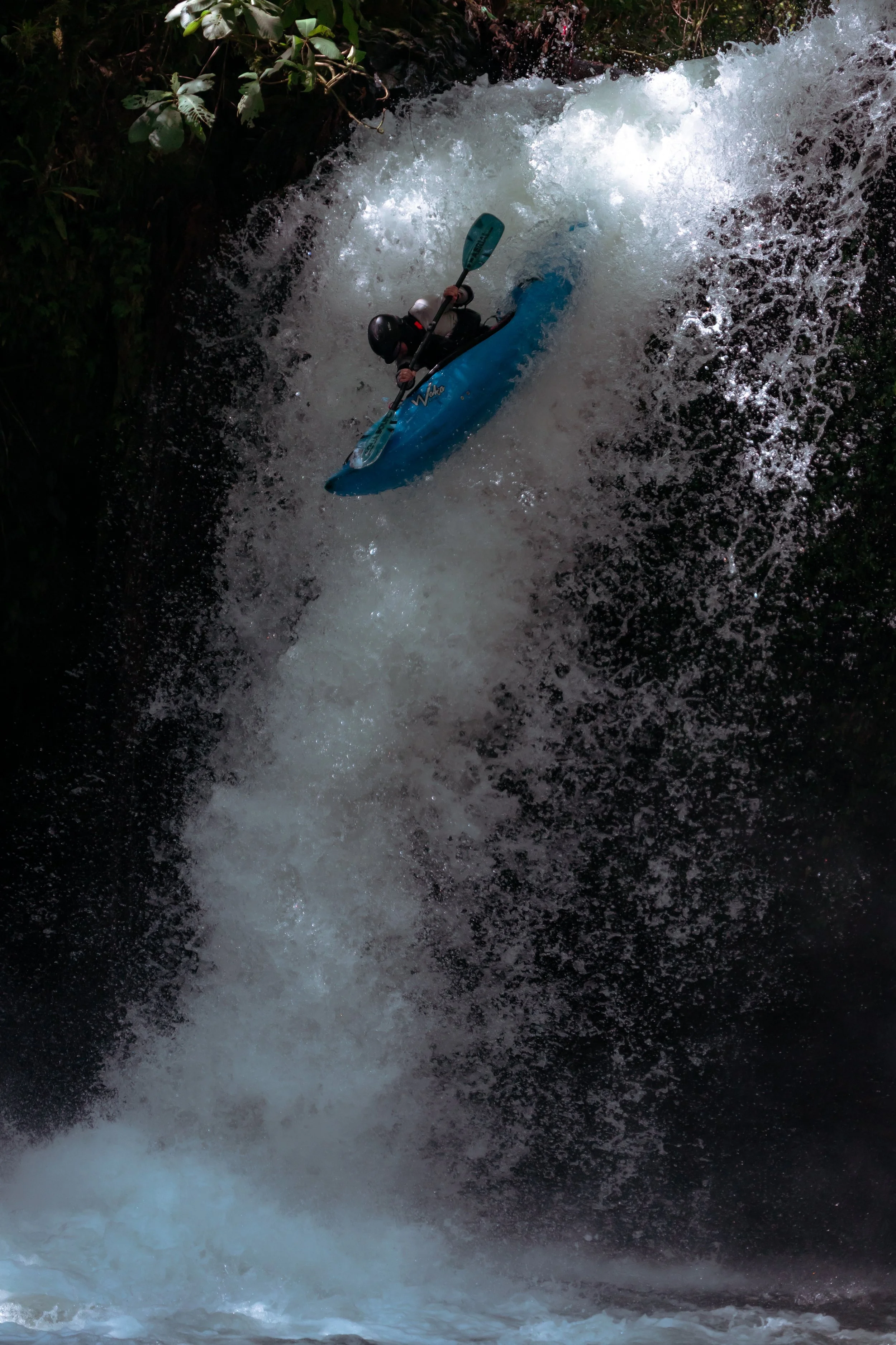 Person kayaking down a waterfall.