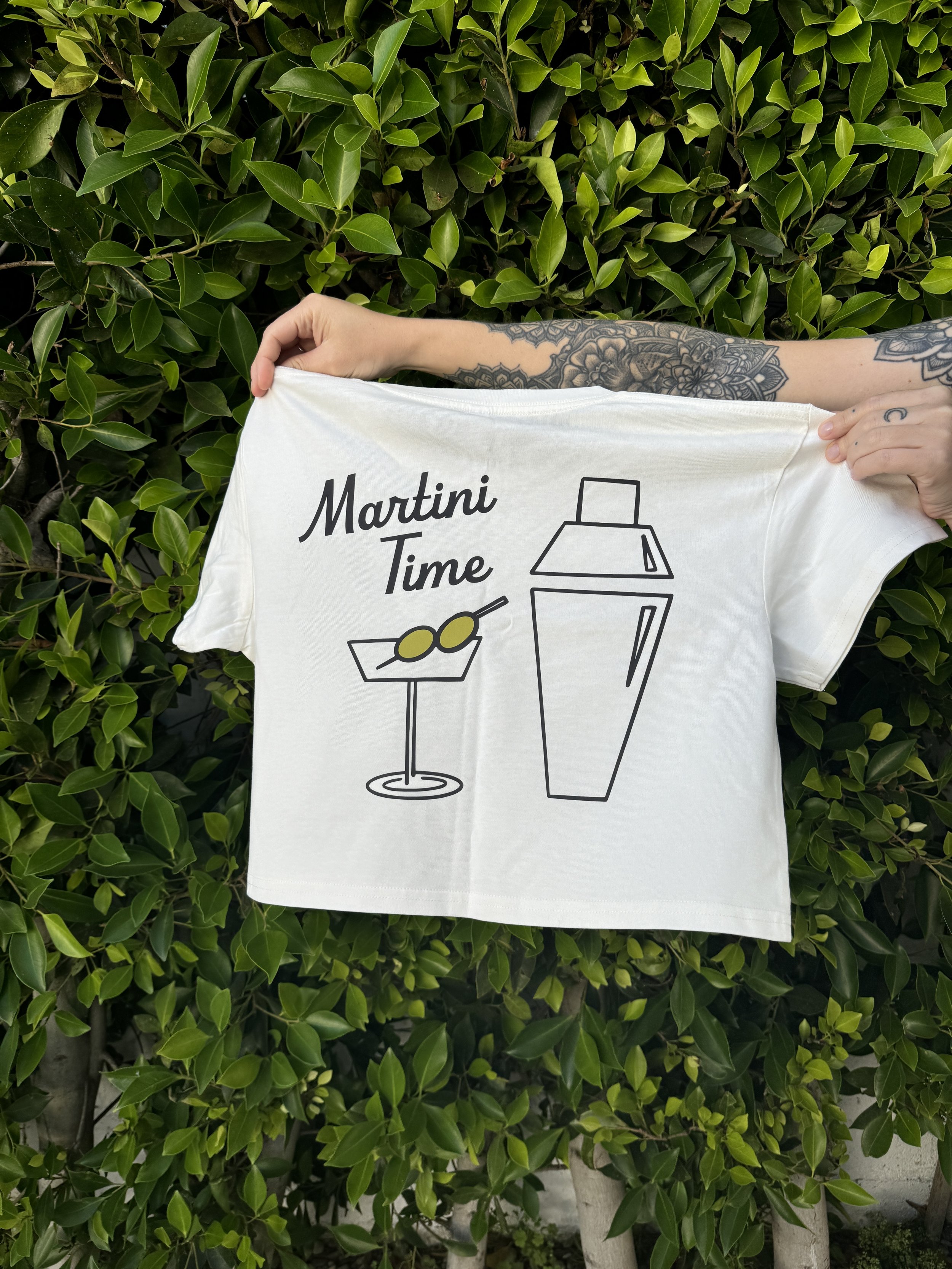 hands holding up a crop top in off white martini graphic that says martini time