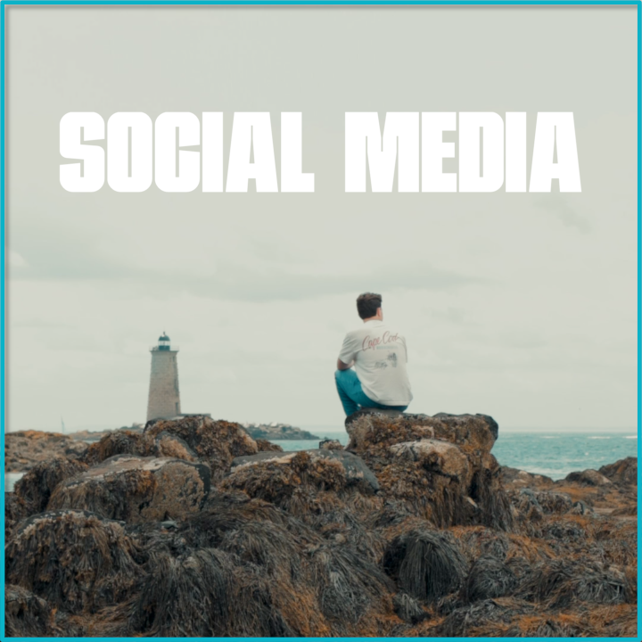 A person sitting on rocks near the ocean with a lighthouse in the background, under a cloudy sky, with the text 'Social Media' at the top.