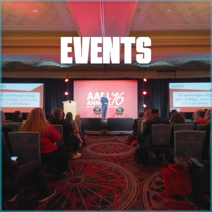 Conference room with attendees seated facing a stage displaying multiple screens, with a speaker presenting at the AACR Annual Meeting 2016.