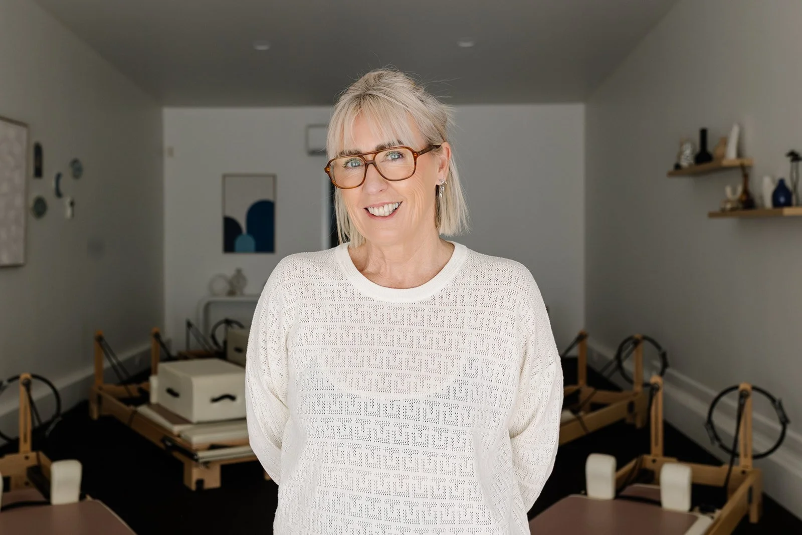 Simone, the founder of See Pilates, standing in the studio with the reformer machines in the background.