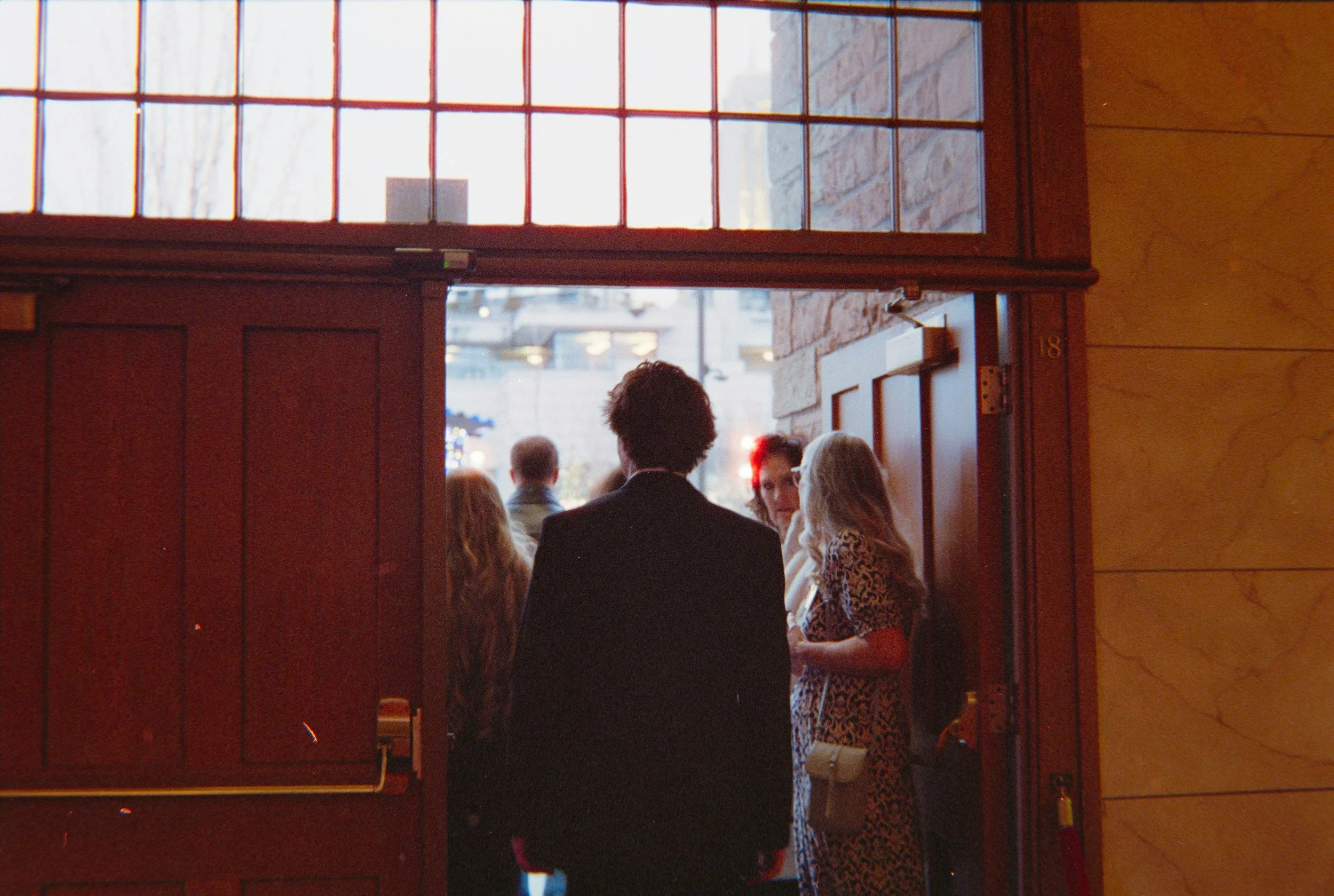 Person standing outside a social setting, hesitating before taking the first step toward meeting new people.