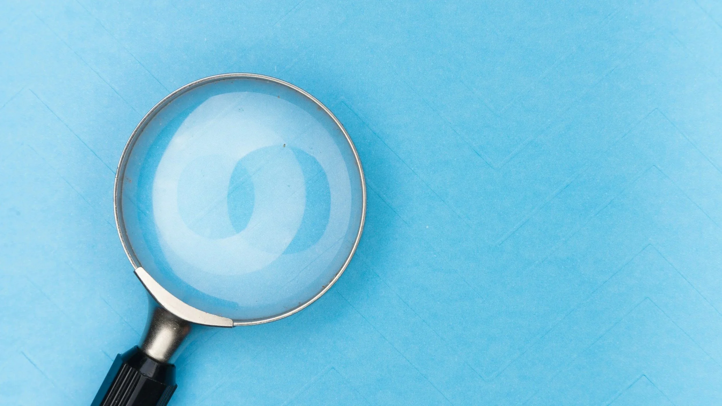 A magnifying glass resting over a blue background.