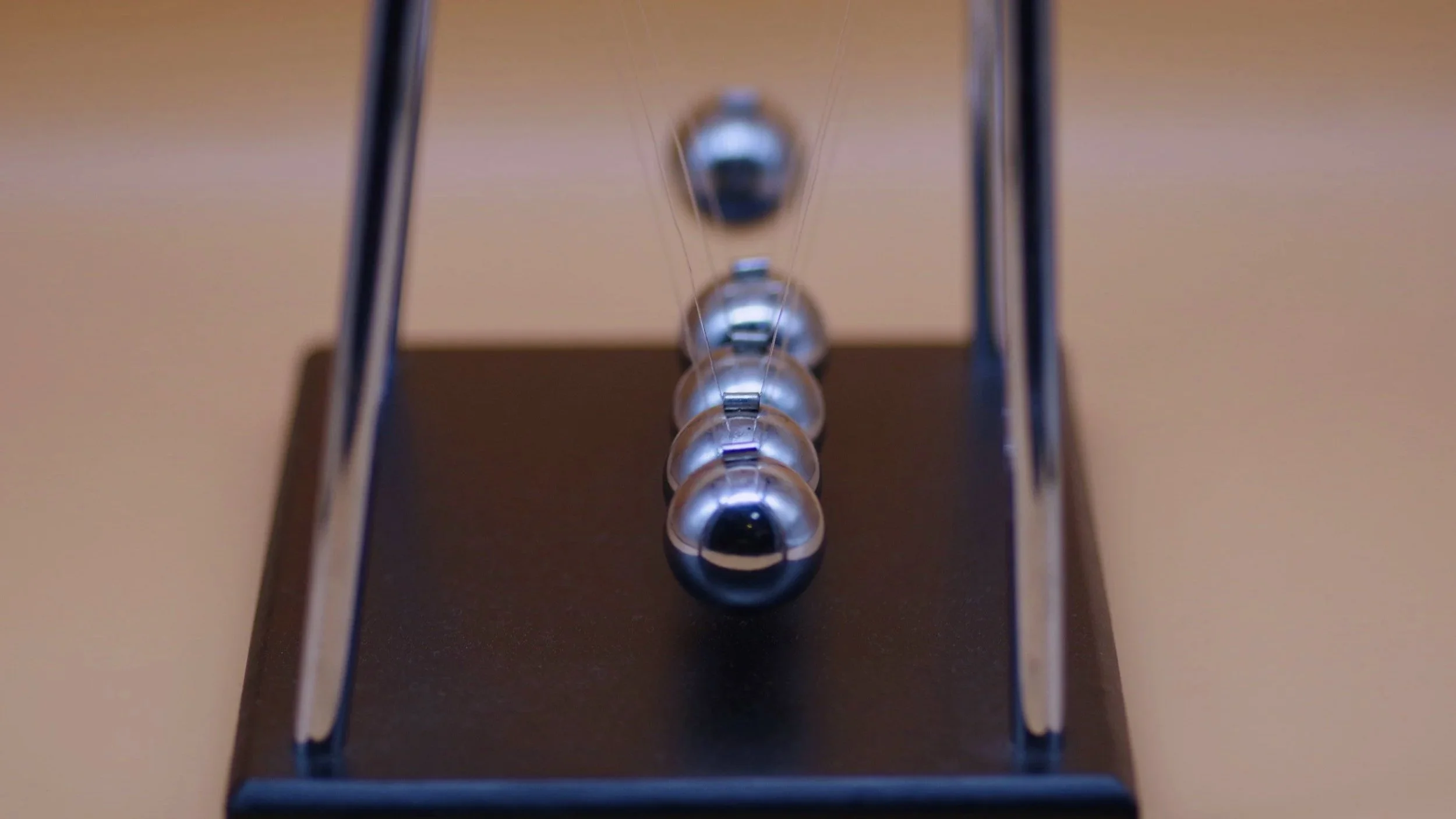 Newton’s cradle in motion, symbolizing momentum, rhythm, and the gradual development of social confidence.