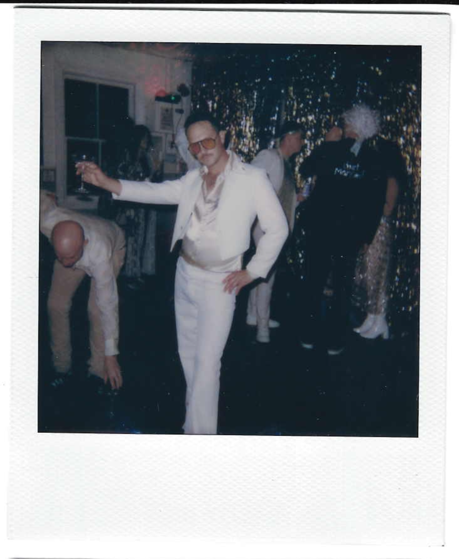 People dressed in 70s or disco-style clothing at a party or celebration with a sparkly backdrop.