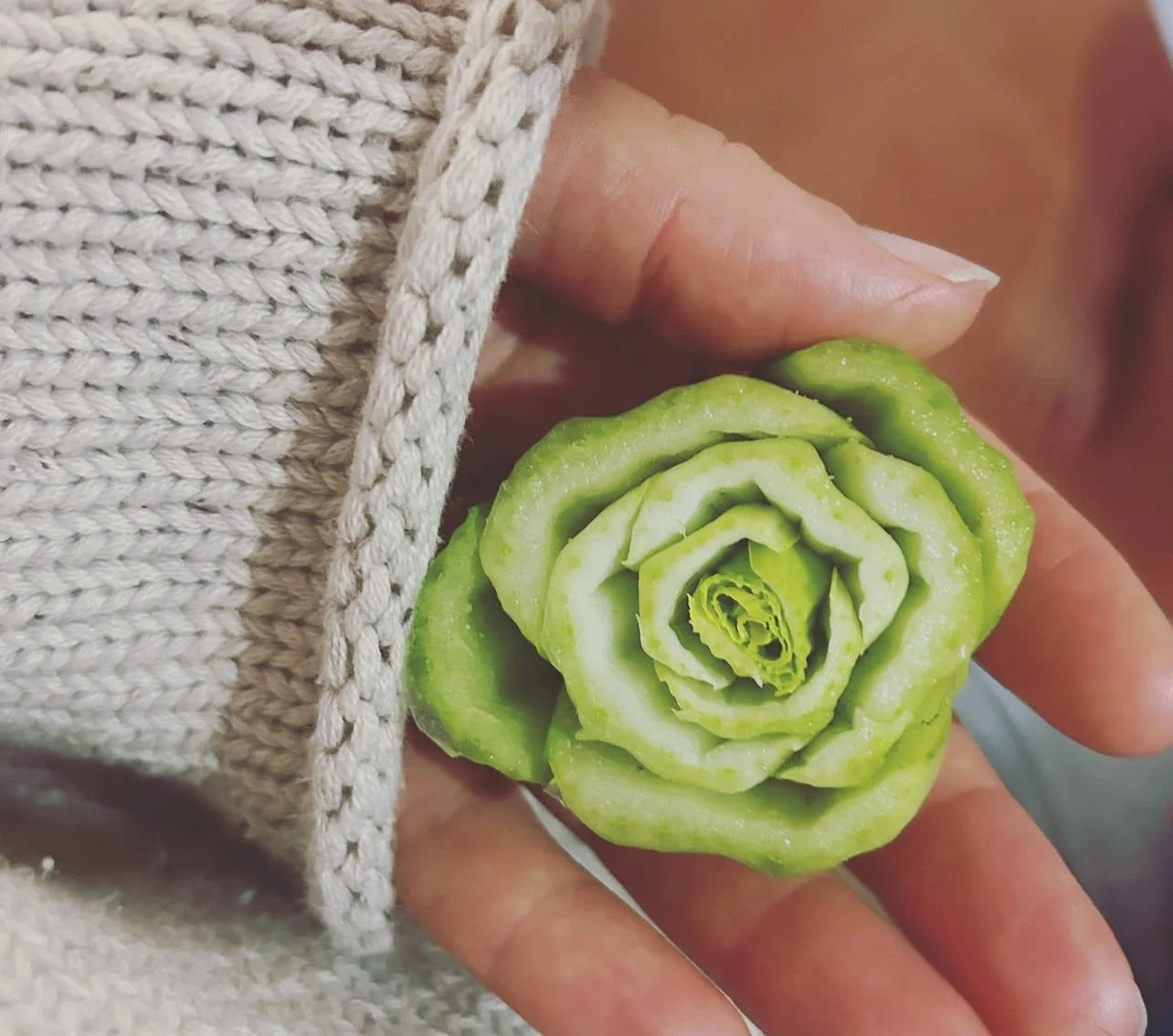 Hand holding a carved vegetable shaped like a rose.
