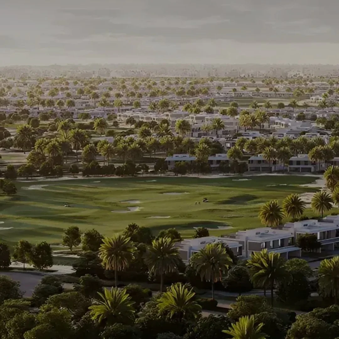 A golf course surrounded by palm trees and residential buildings under a cloudy sky.