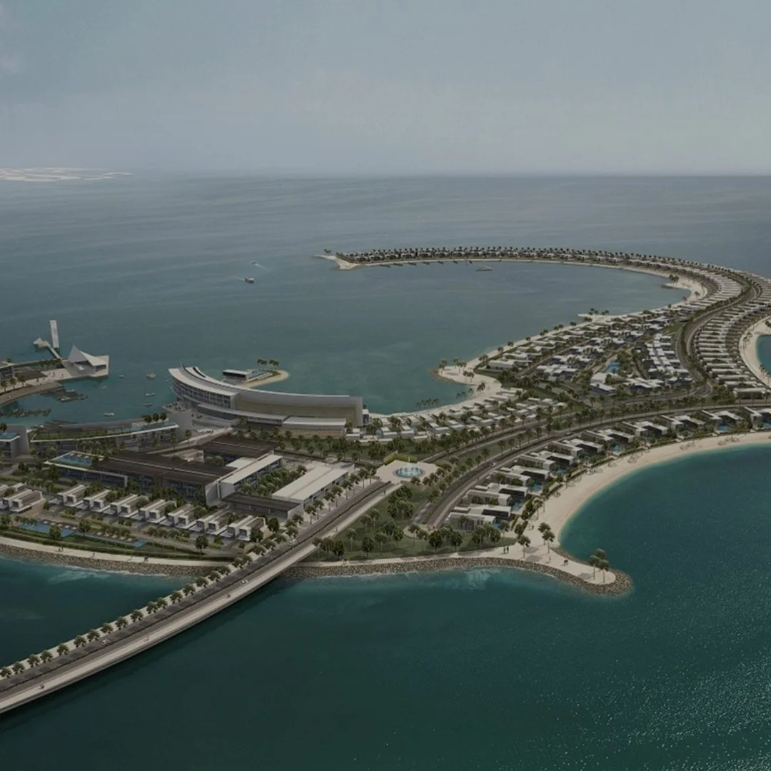 Aerial view of a coastal city with modern buildings, roads, and a curved shoreline, overlooking the ocean with calm waters.