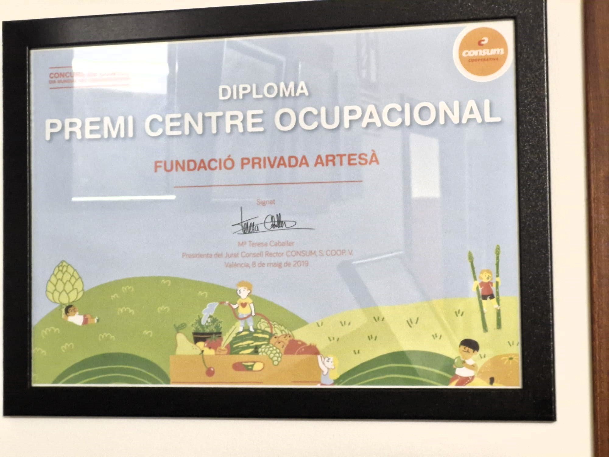 Certificado enmarcado que otorga un premio en un centro ocupacional, con ilustraciones de niños en un campo con árboles, verduras y frutas, y un logotipo de cooperativa en la esquina superior derecha.
