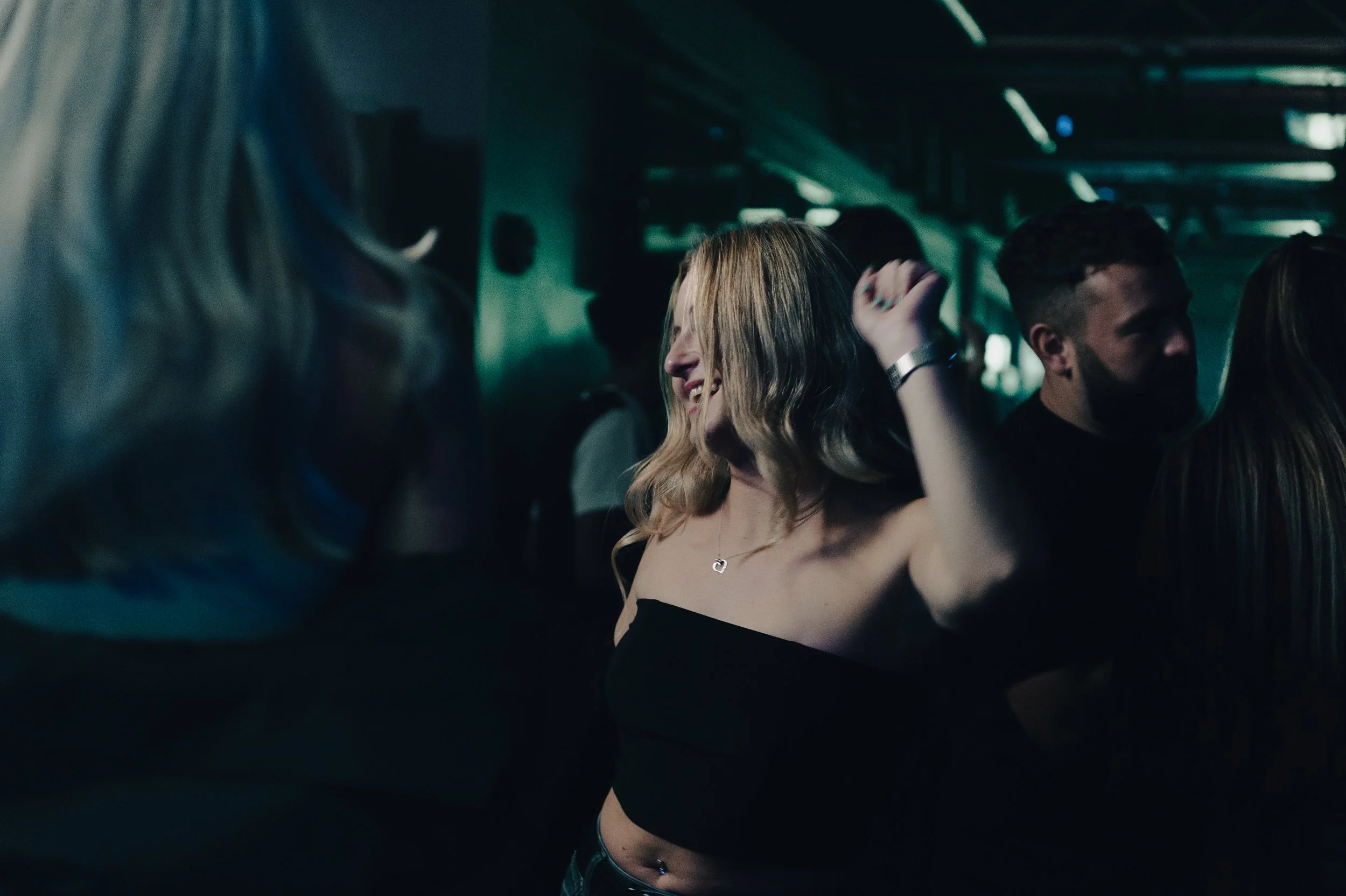 People dancing in a dimly lit club or party environment.