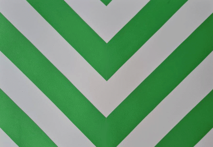 Close-up of a gray floor with green and white V-shaped stripes forming a chevron pattern.