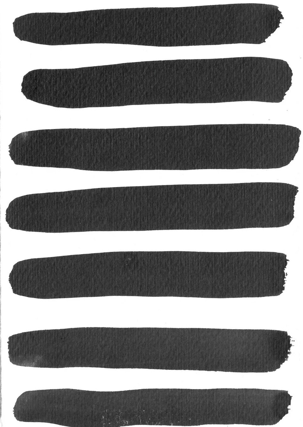 Multiple black marker strokes on white paper, arranged horizontally.