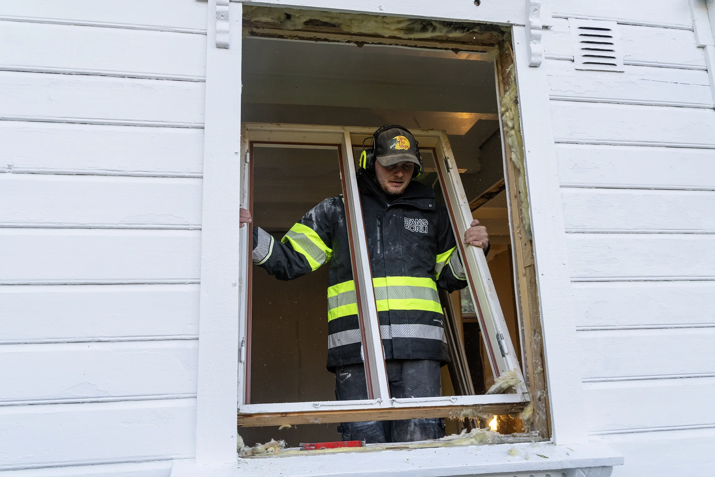 A construction worker inside a house installing a window frame.