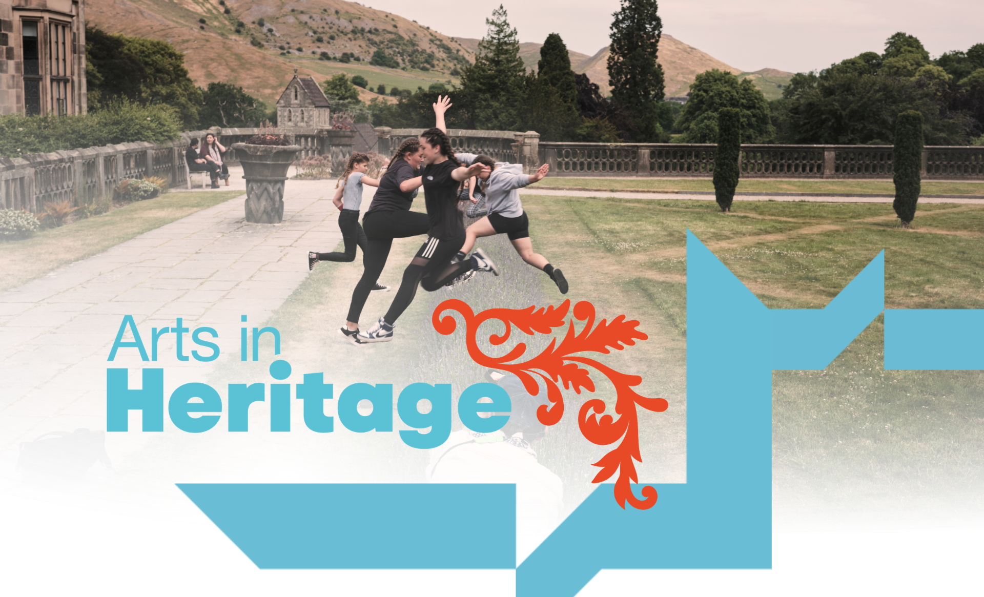 Children jumping and playing outdoors at a heritage site with mountains, trees, and historic buildings in the background, with overlay text that says "Arts in Heritage."