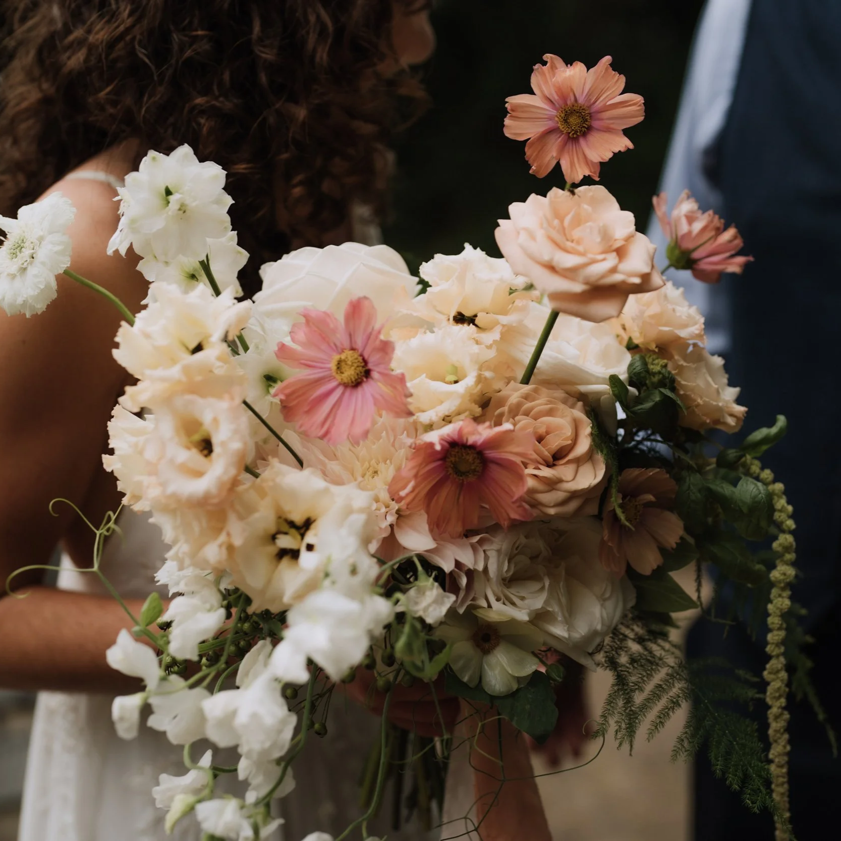 bride holding a white, cream and blush bridal bouquet, for a Norfolk countryside wedding