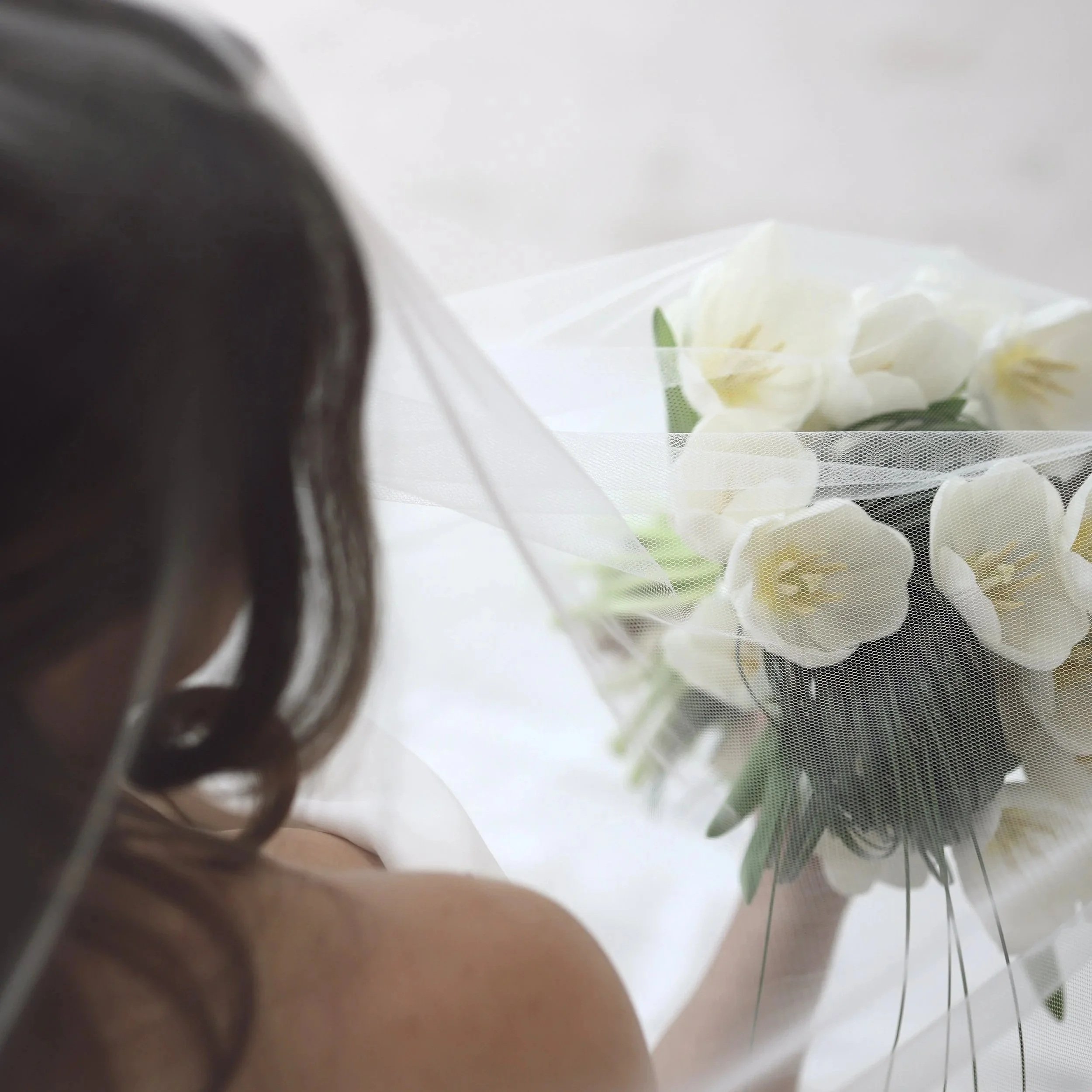 bride holding a white tulip bridal bouquet underneath a sheer veil