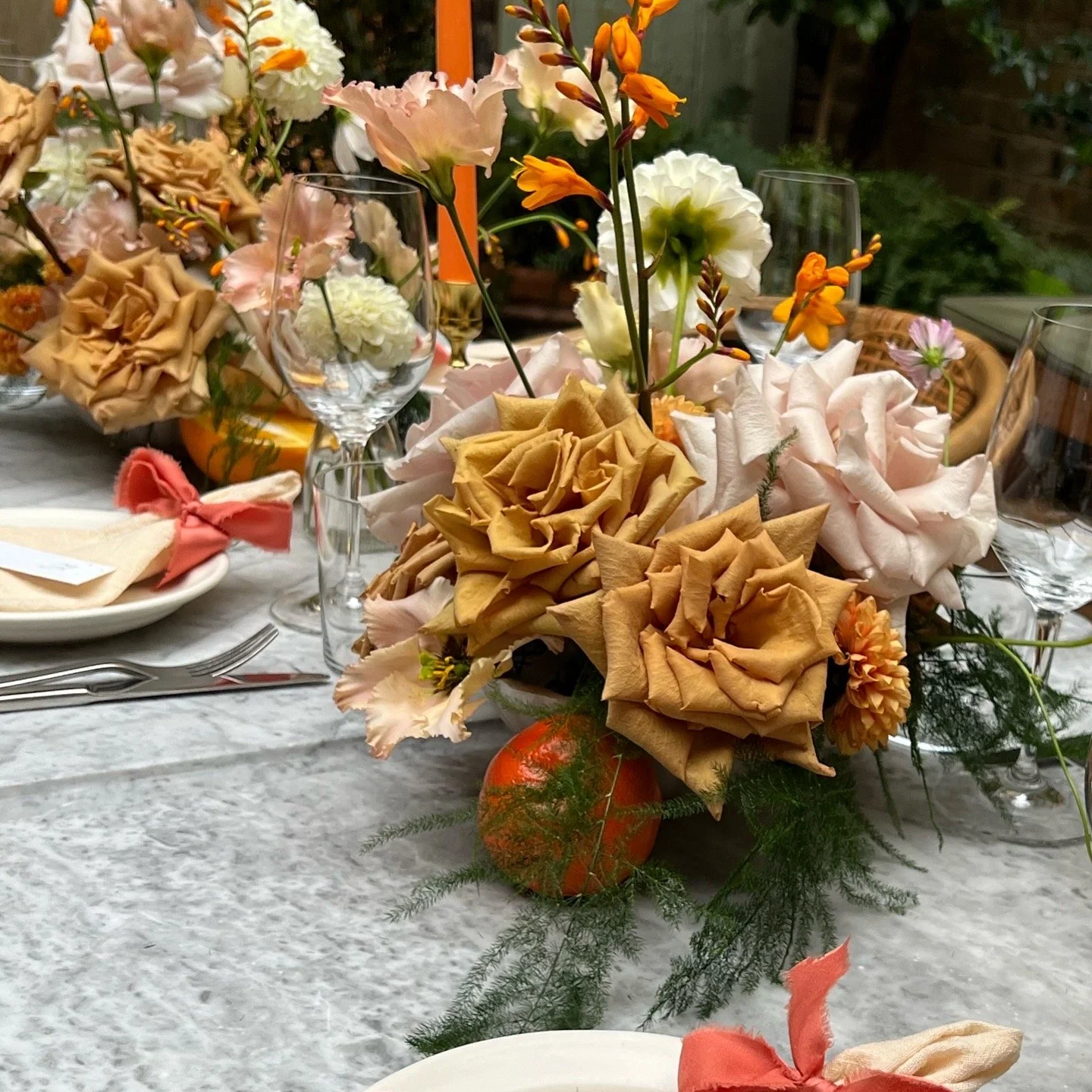 wedding table flowers, featuring toffee roses, white and orange dahlias, ferns, lisianthus and oranges