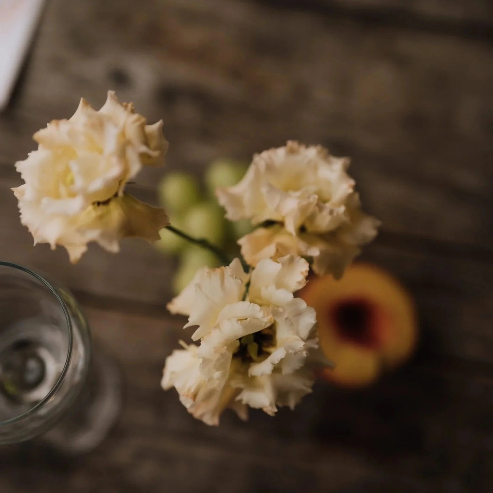 peach alissa lisianthus bud vase with grapes and a cut peach on a wooden table, for a Norfolk countryside wedding