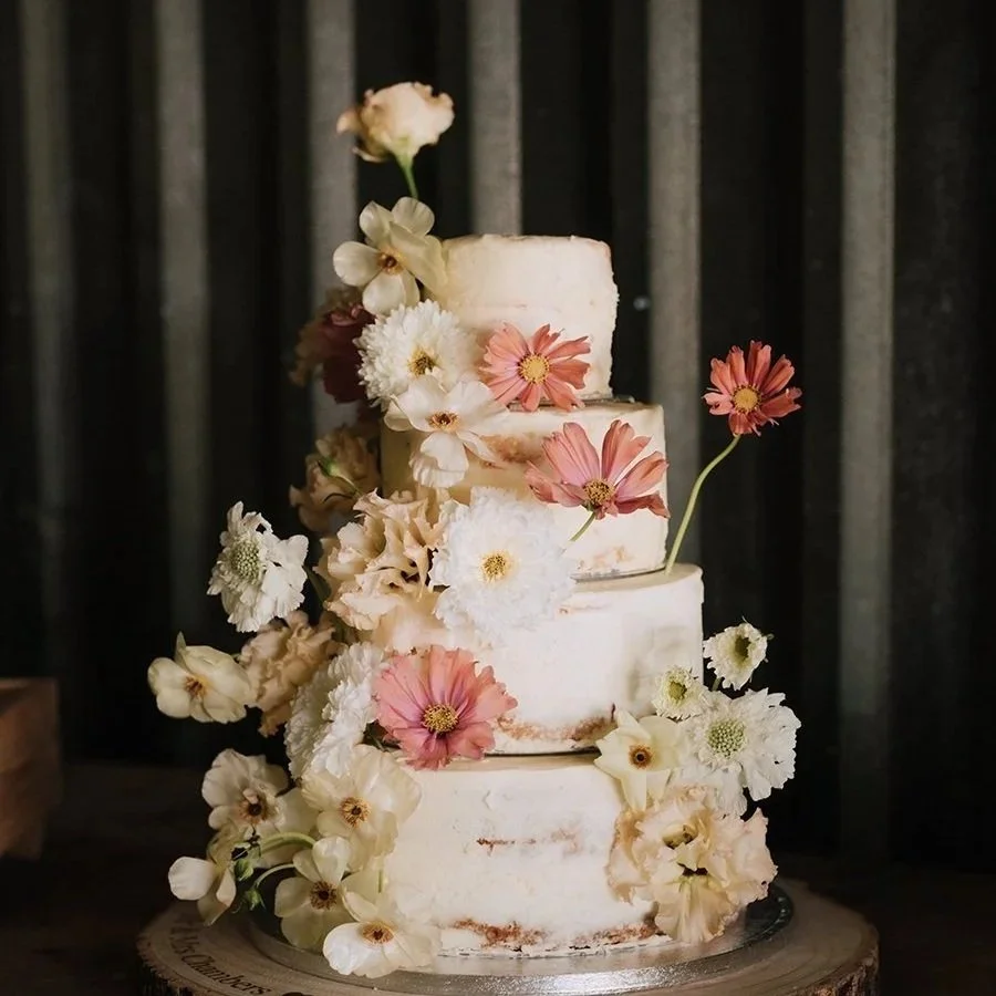 4 tier wedding cake decorated with white, cream and peach fresh flowers, for a countryside Norfolk wedding