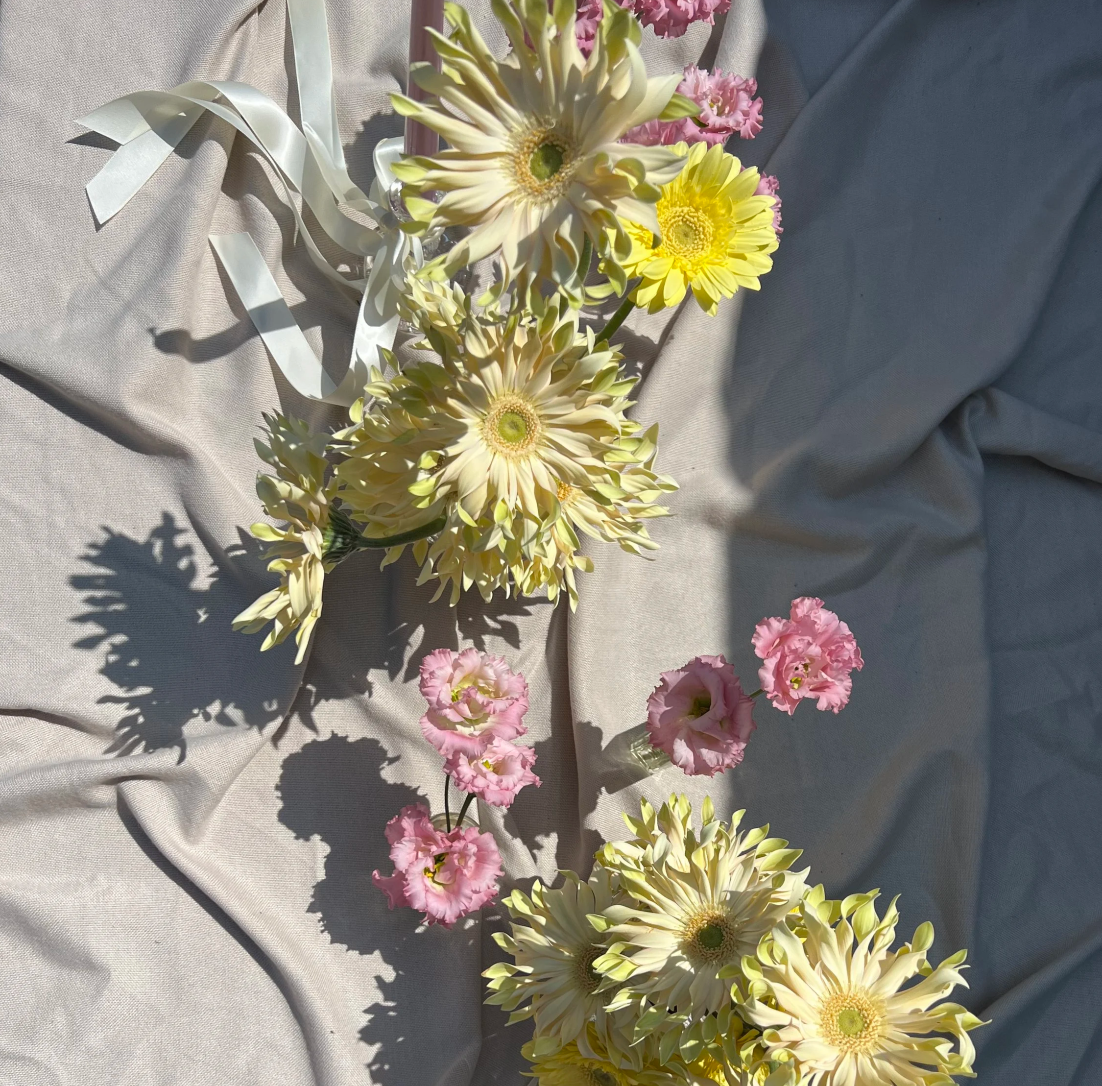 pasta gerberas, pink lisianthus and satin ribbons, arranged along a table for a summer wedding