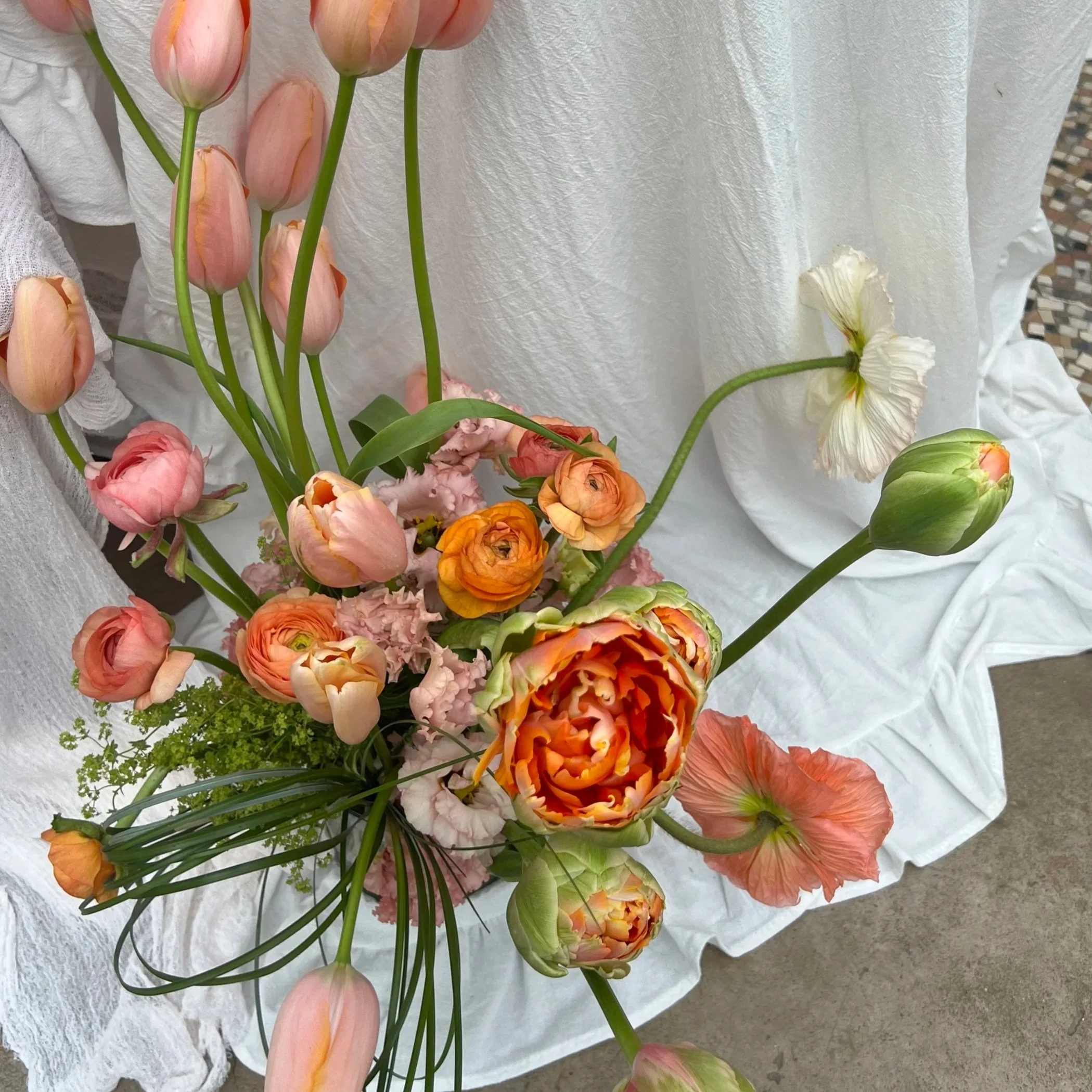 fun floral arrangement of peach and orange french tulips, ranunculus and icelandic poppies