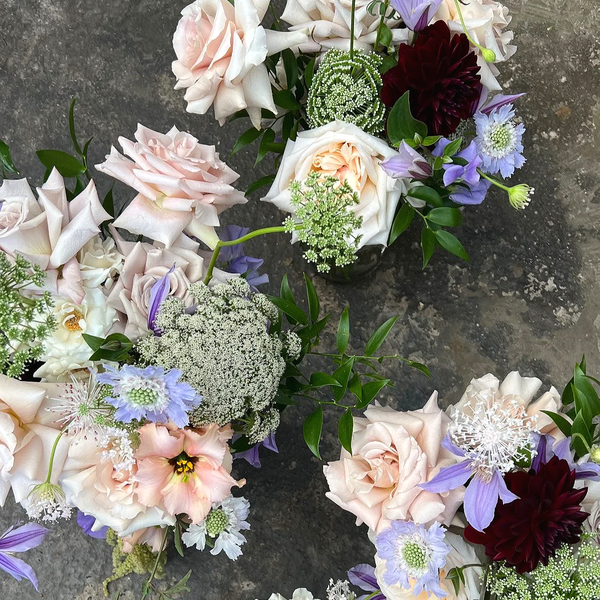 Bridal and bridesmaids bouquets in pastel blush, lilac and deep burgundy tones, including scabious, dahlias, roses, clematis and ammi, for a countryside summer wedding