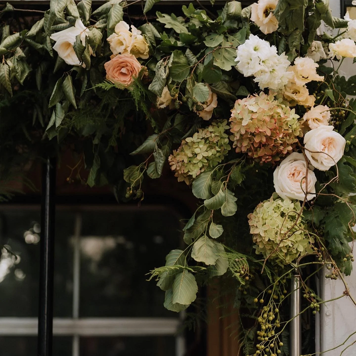 Late summer wedding floral arrangement featuring hydrangeas, roses, lisianthus and seasonal foliage
