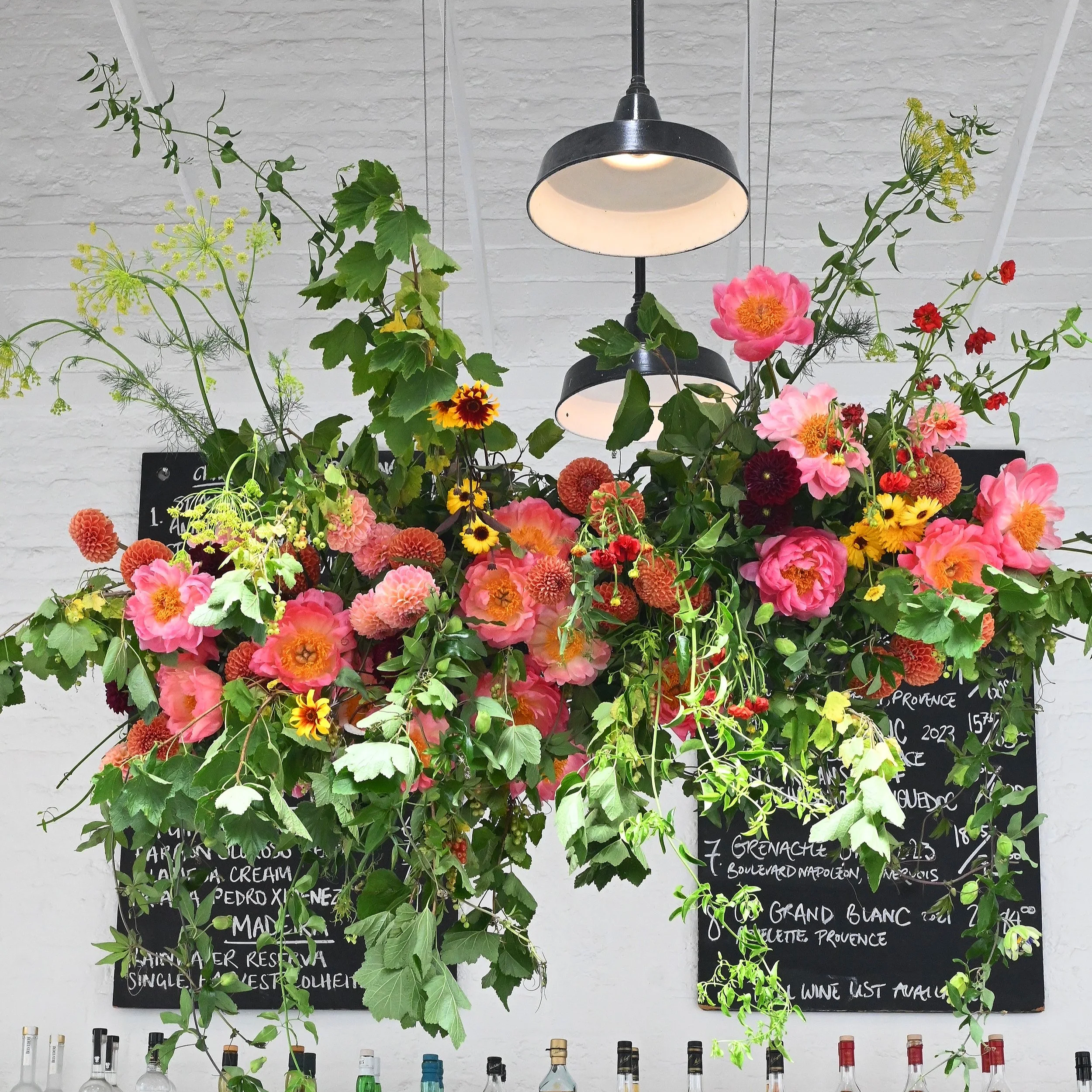 Big, wild, colourful flower cloud for a June wedding at St John restaurant, featuring lush greenery and an abundance of seasonal flowers