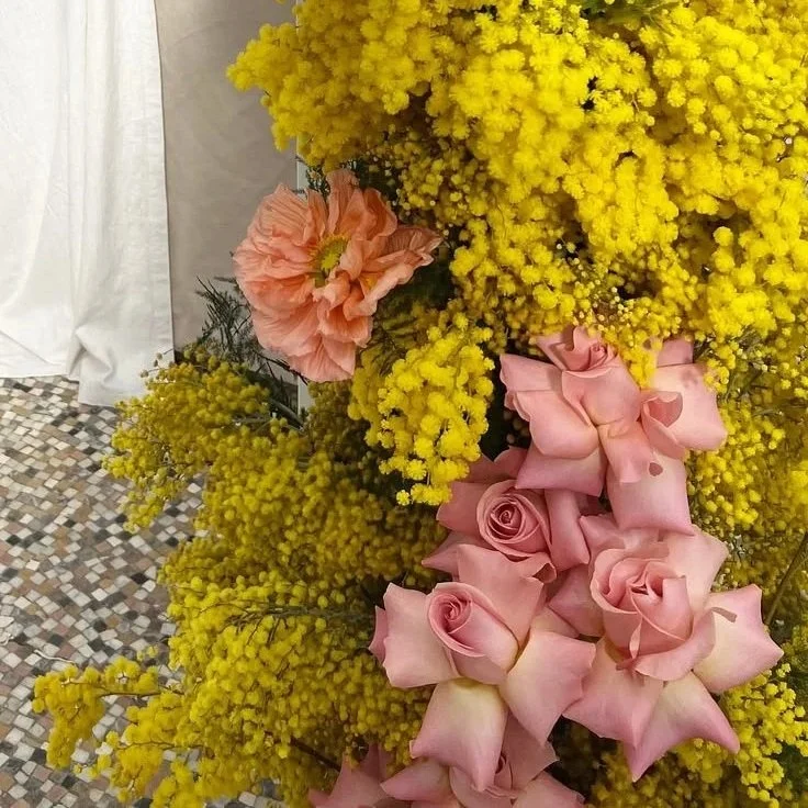 close up of a floral arrangement made with yellow mimosa, peach poppies and pale pink reflexed roses, in Norwich in Spring