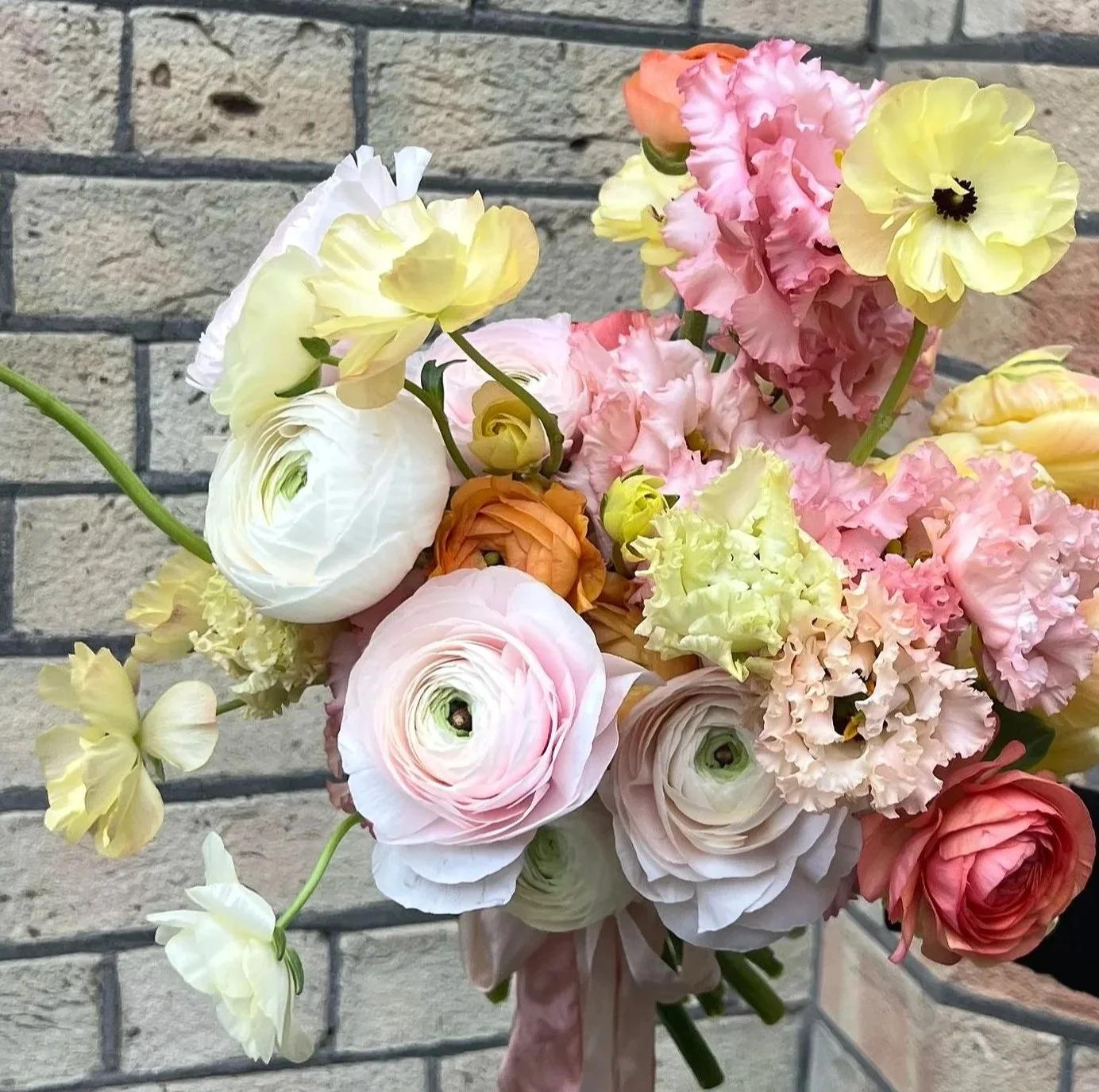 cream, pink, orange and lemon spring flower bridal bouquet, including hanoi ranunculus, butterfly ranunculus and alissa lisianthus