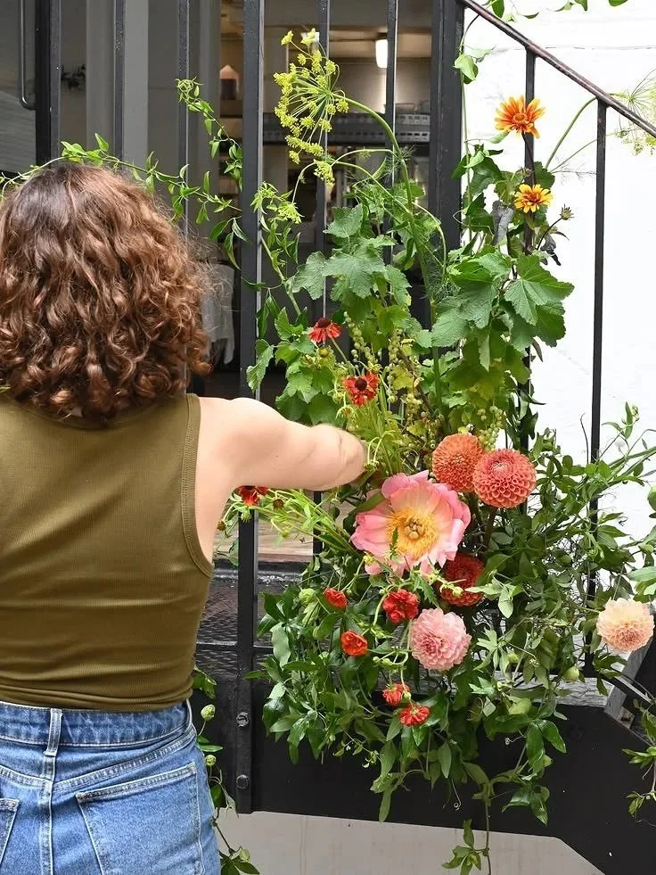 Florist designing an arrangement on a staircase for a city restaurant wedding reception