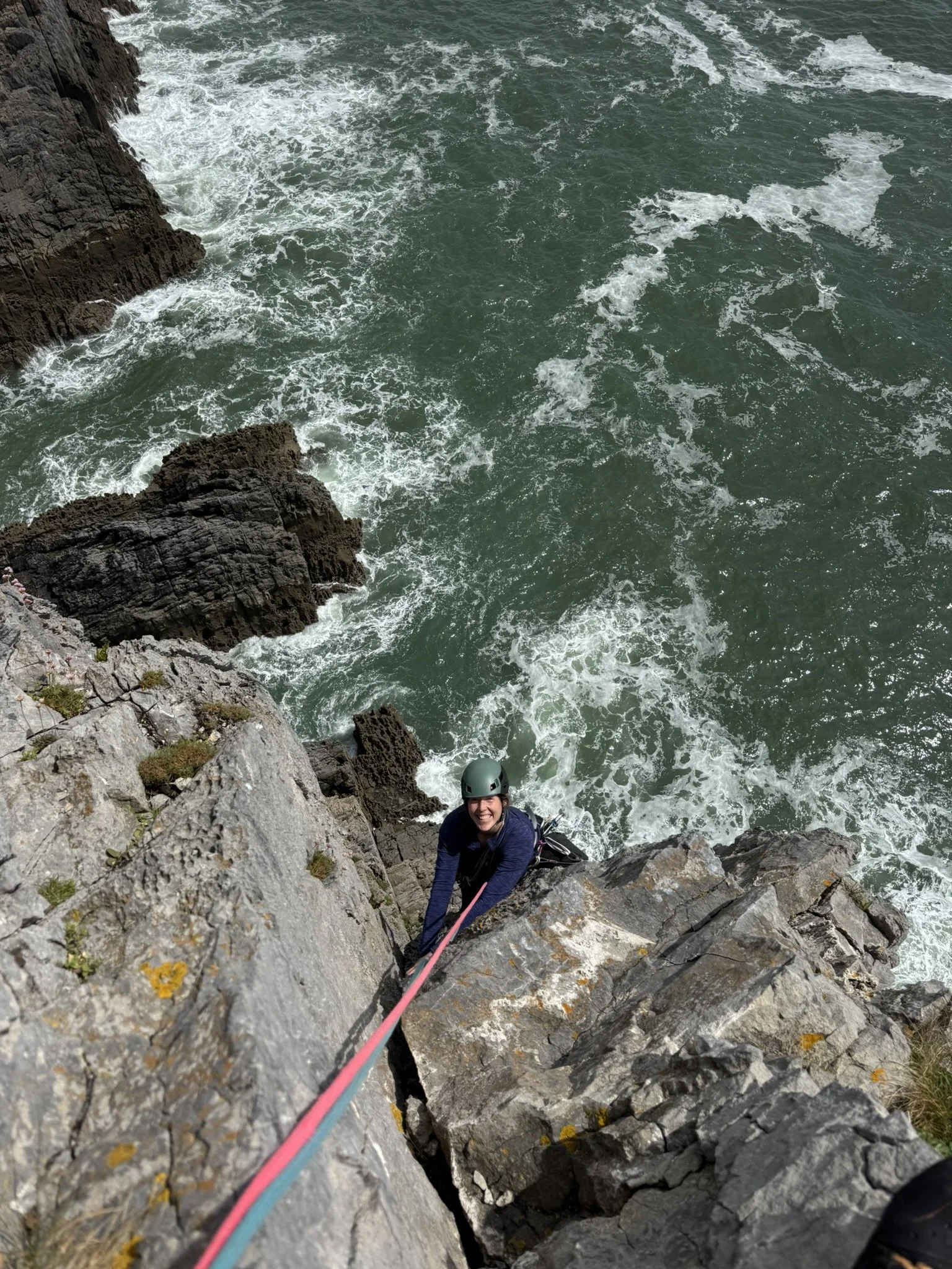 A lady rock climbing on sea cliffs in pembrokeshire