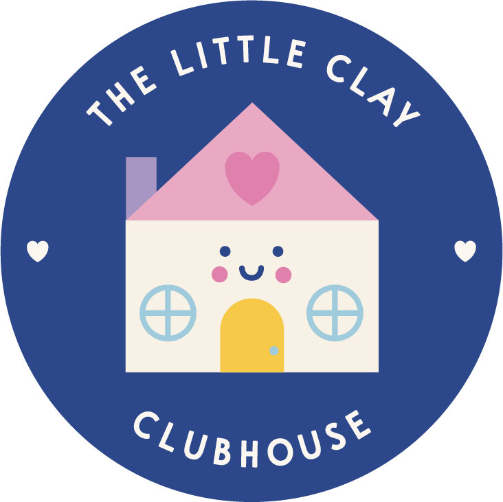A circular logo with a blue background featuring a cute, smiling house with a pink roof, a yellow door, and two round windows. The house has a pink heart on the roof. The text around the circle reads 'The Little Clay Clubhouse.'