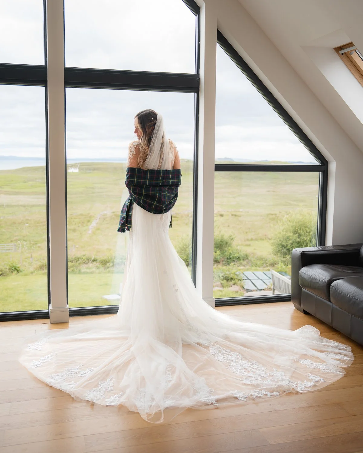 Bride standing by floor to ceiling window looking over her shoulder.