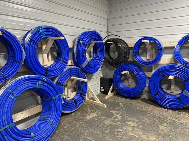 Coiled CTS and IPS waterline stored on wooden racks in a metal-walled room.