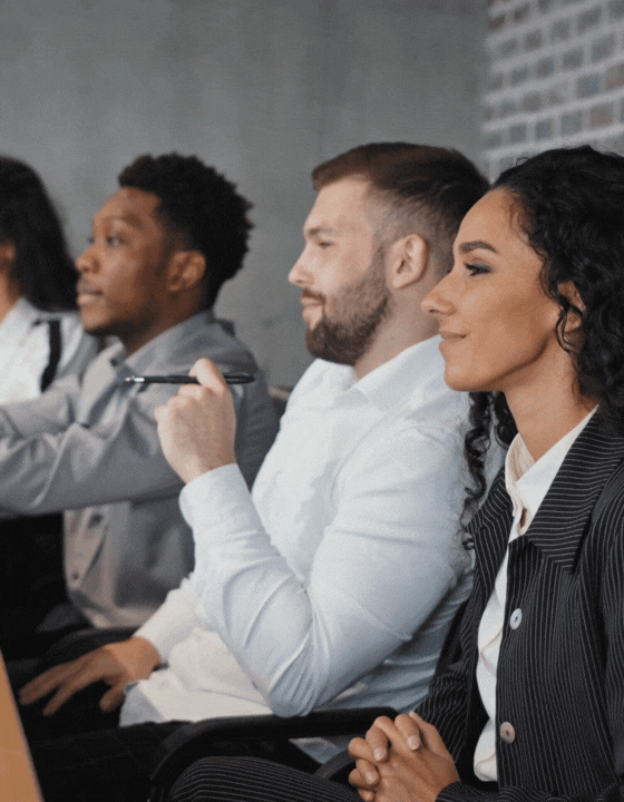 Group of professionals in a meeting, with one person raising their hand.